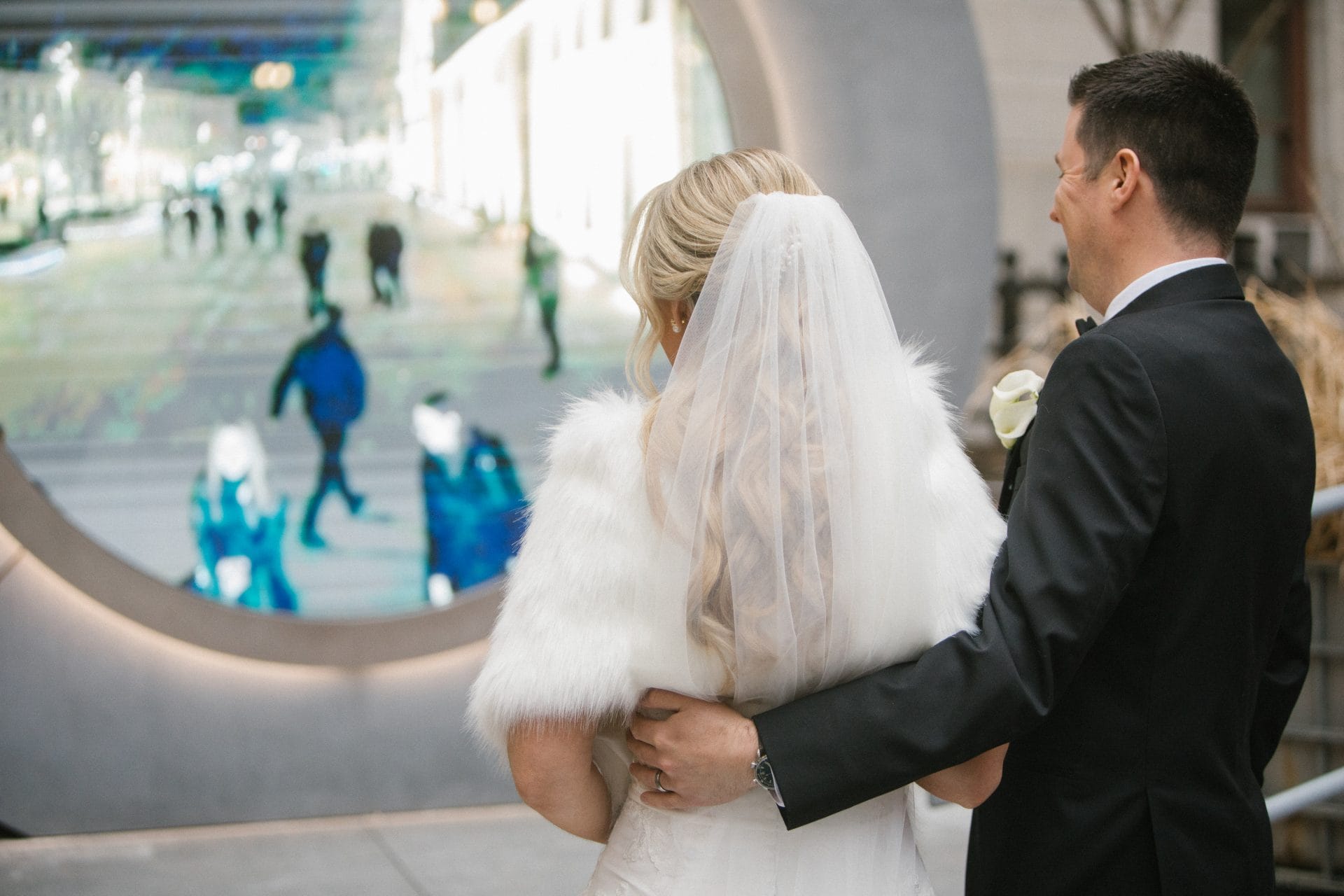 Bride and groom looking through circular window at City Hall toward Broad Street