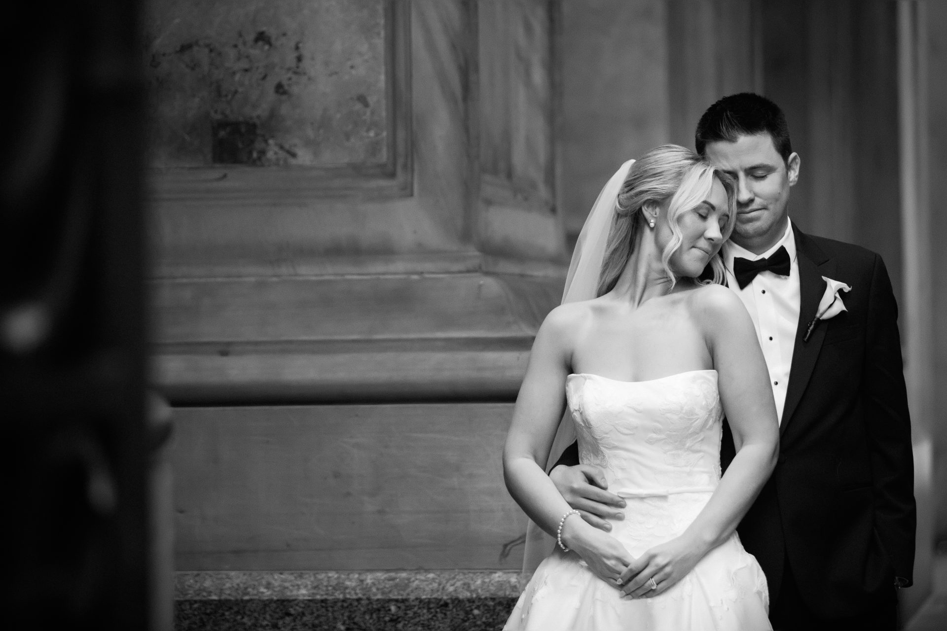 Couple embracing against City Hall stone column with staircase dramatic portrait