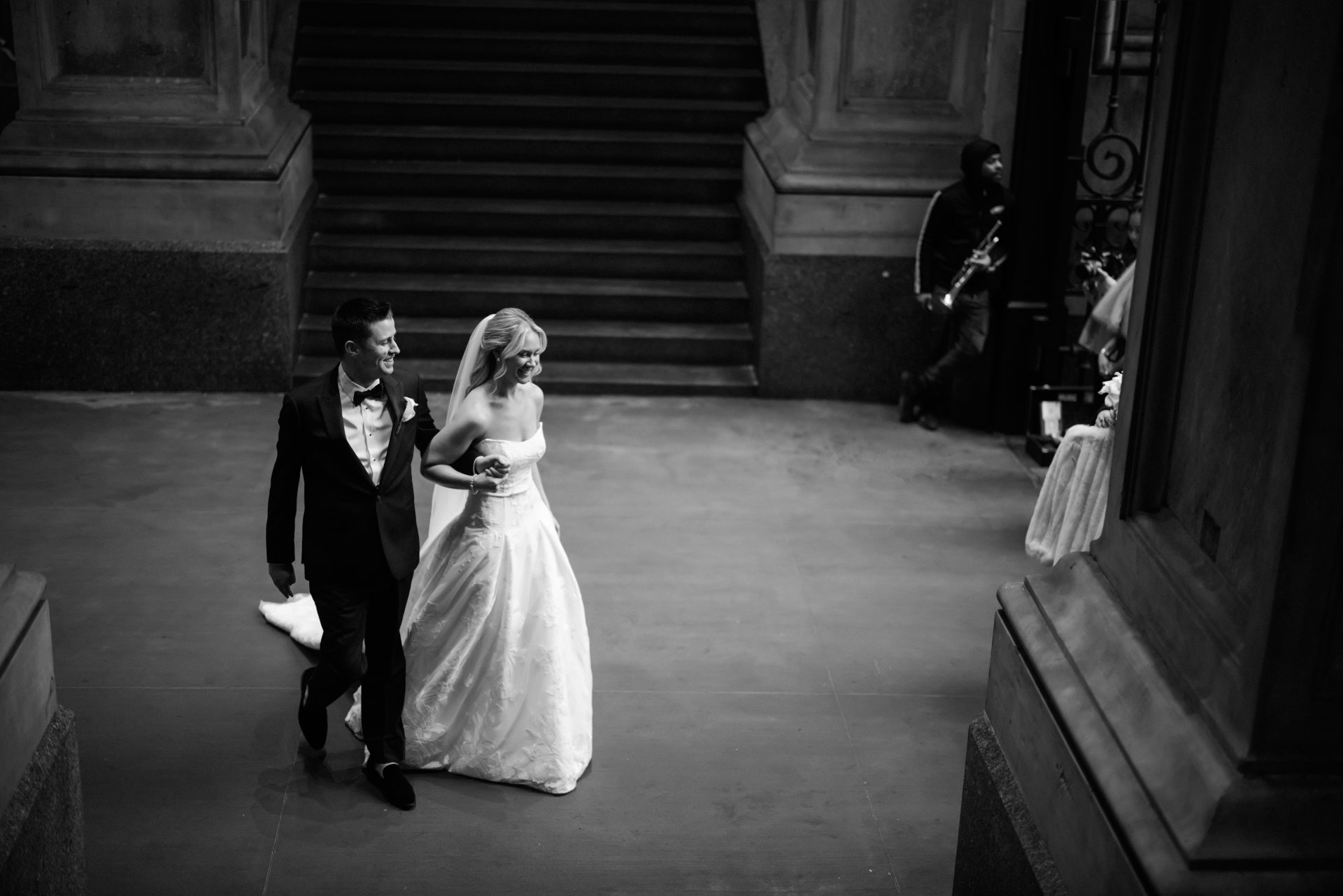 Wide overhead shot of bride and groom walking across City Hall interior floor