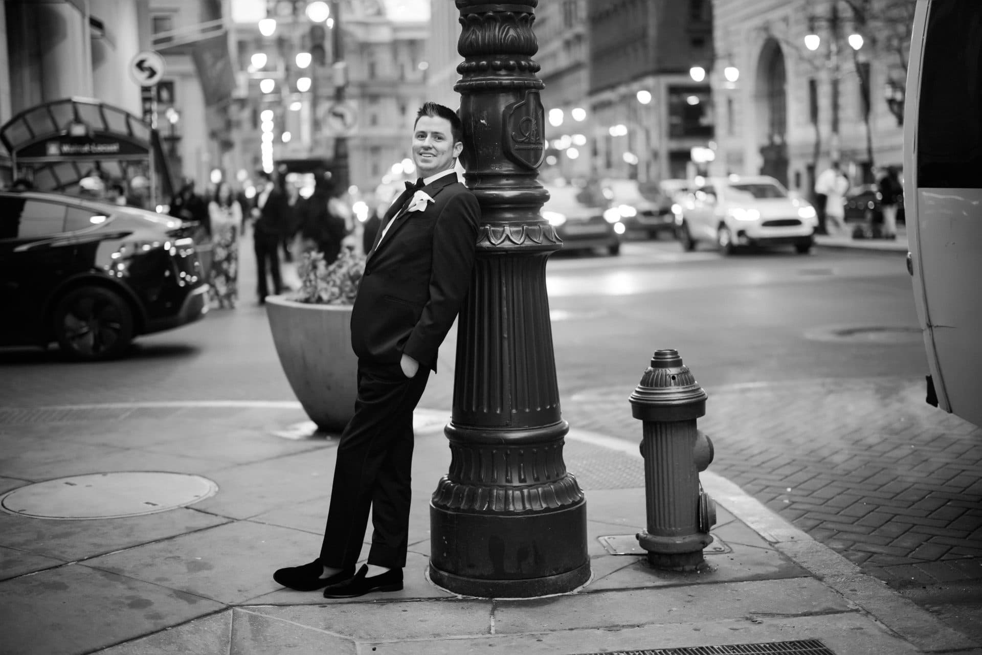 Groom leaning against street lamp post solo portrait Philadelphia city nightlife