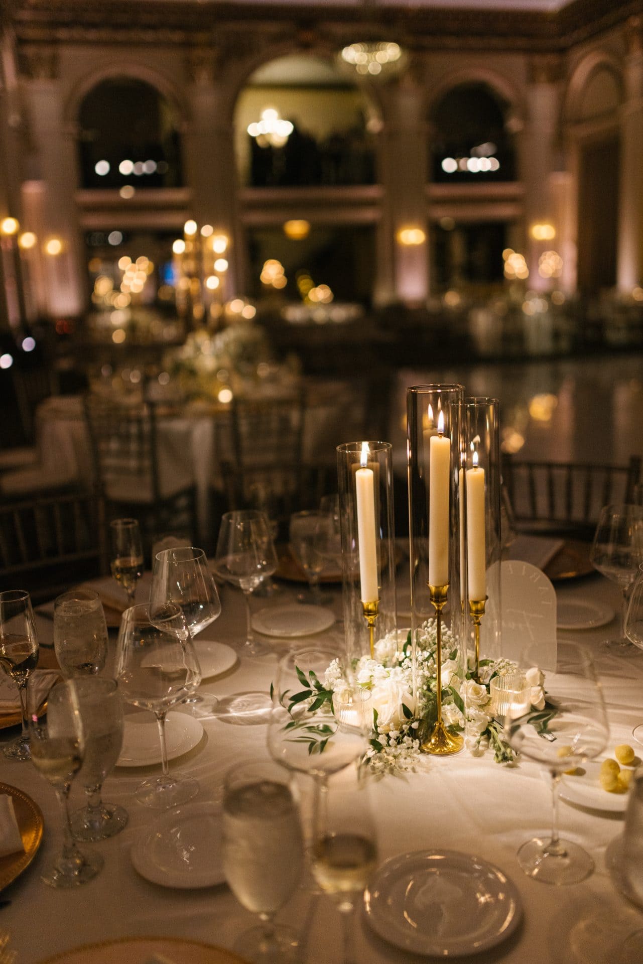 Ballroom at the Ben reception tablescape pillar candles white florals gold chargers