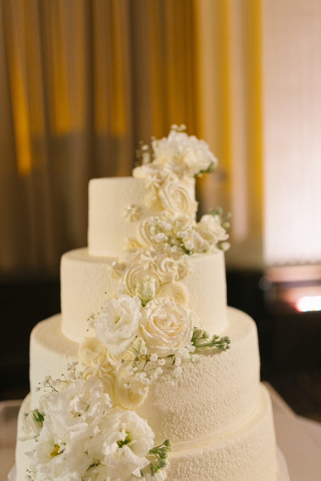Four tier white wedding cake with cascading roses at Ballroom at the Ben