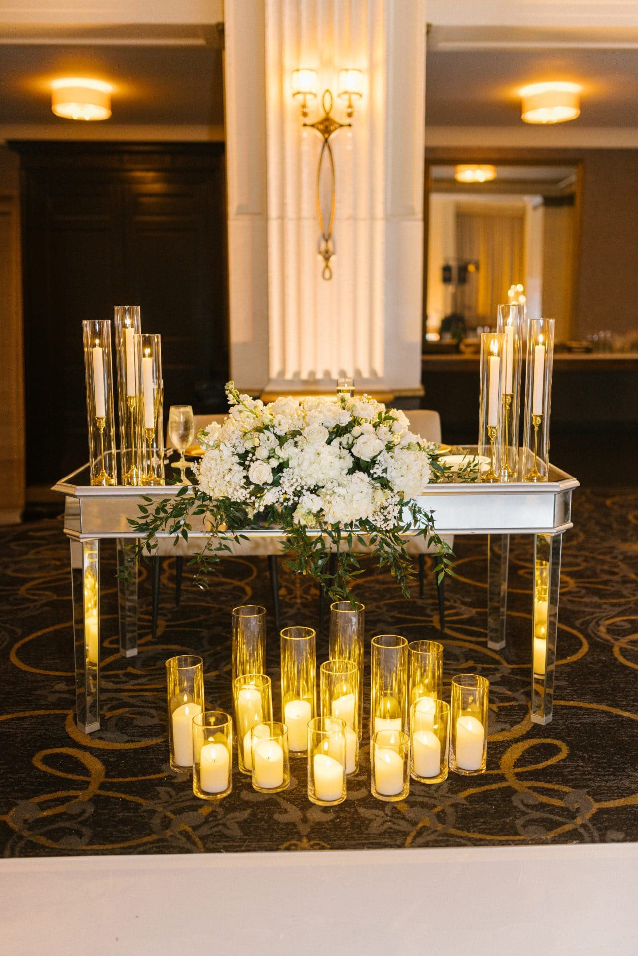 Sweetheart table mirrored display with white hydrangea roses and pillar candles