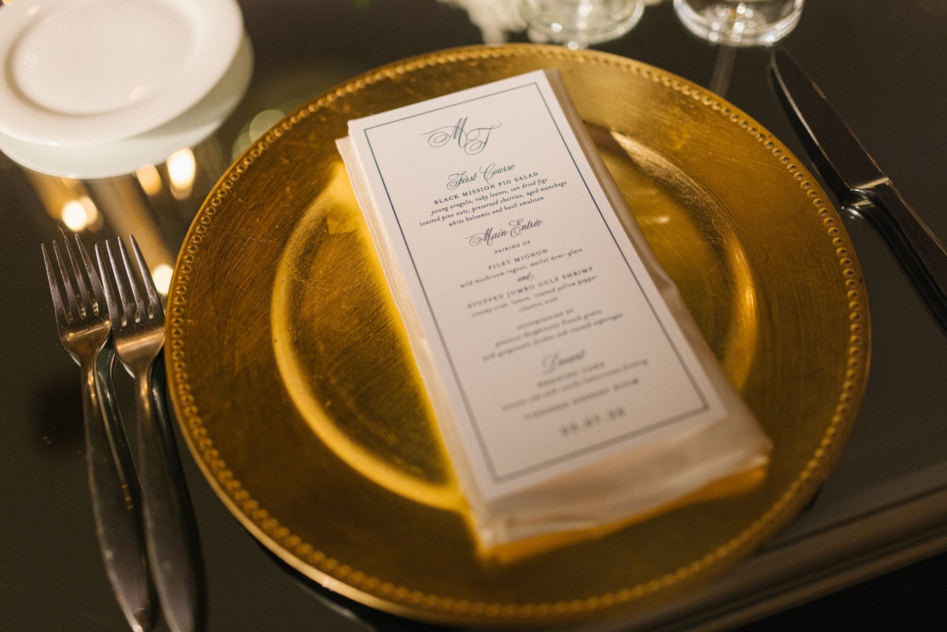 Custom monogrammed menu card on gold charger plate at Ballroom at the Ben reception