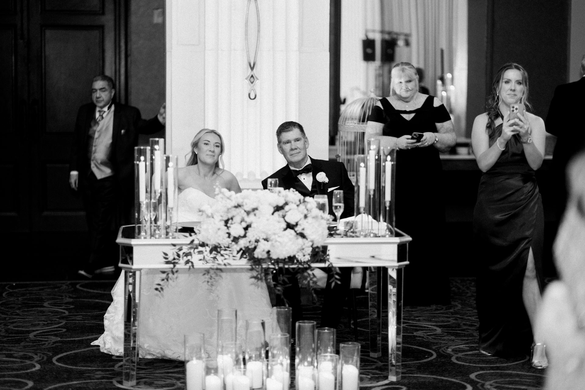 Couple at sweetheart table during toasts guests applauding at Ballroom at the Ben