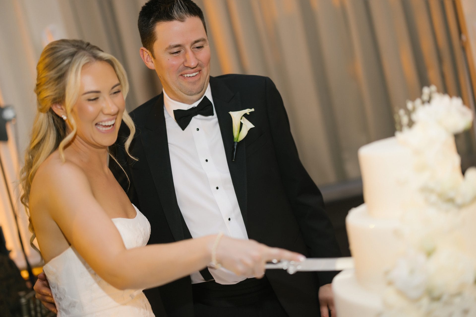 Bride and groom cutting four tier wedding cake laughing at Ballroom at the Ben