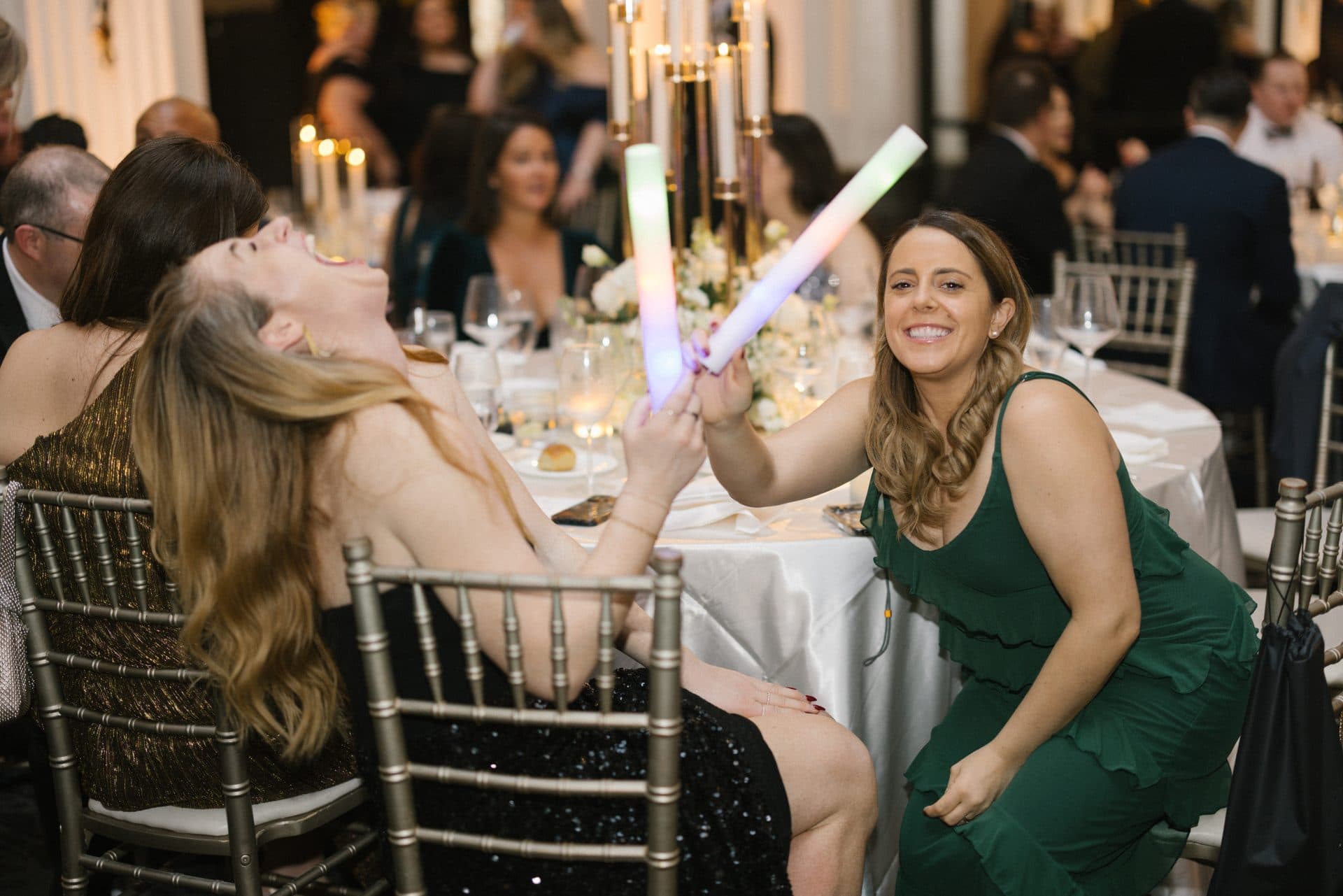 Guests waving LED glow sticks and laughing at Ballroom at the Ben wedding party