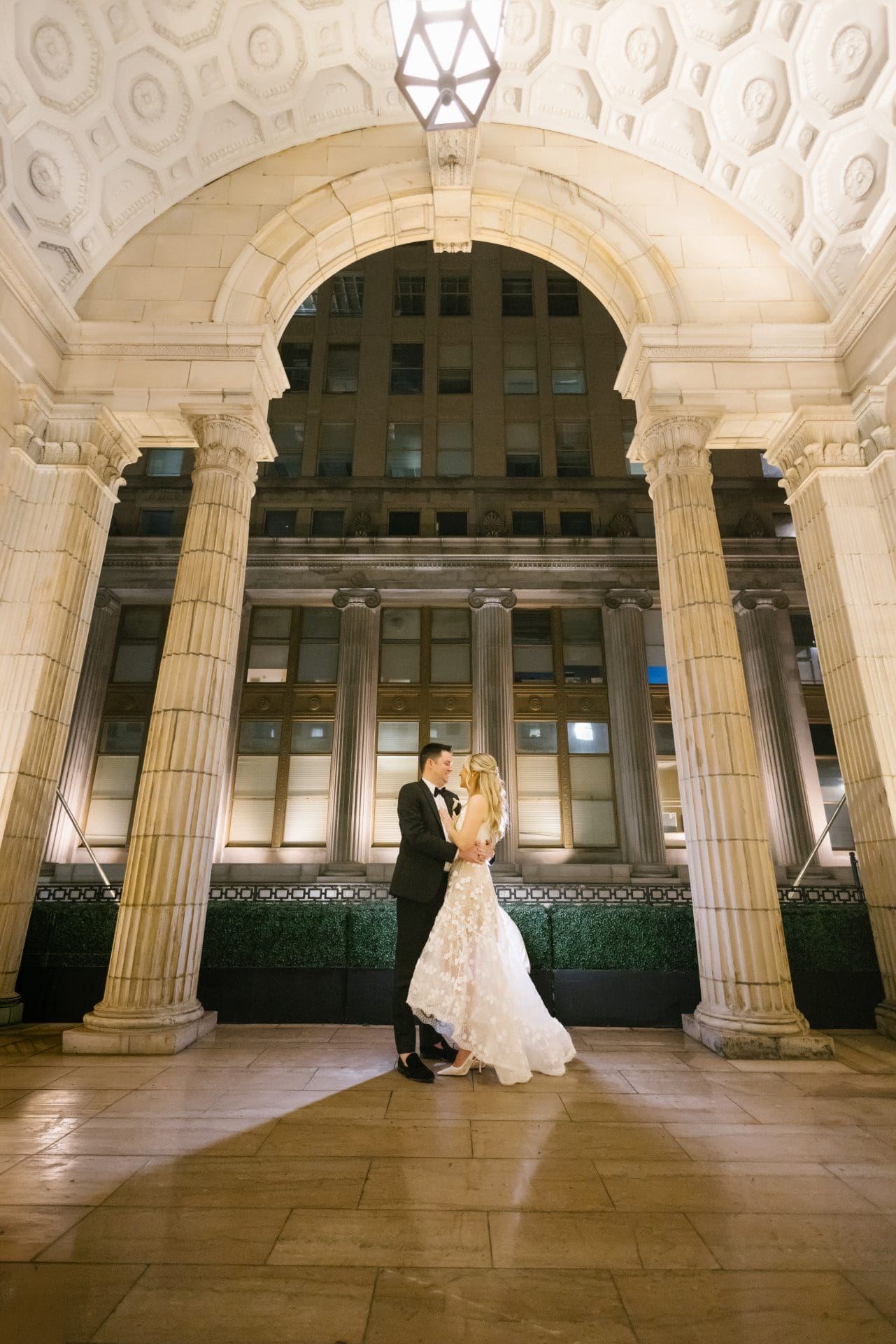 Couple portrait at building entrance at night with dramatic columns at Ballroom at the Ben