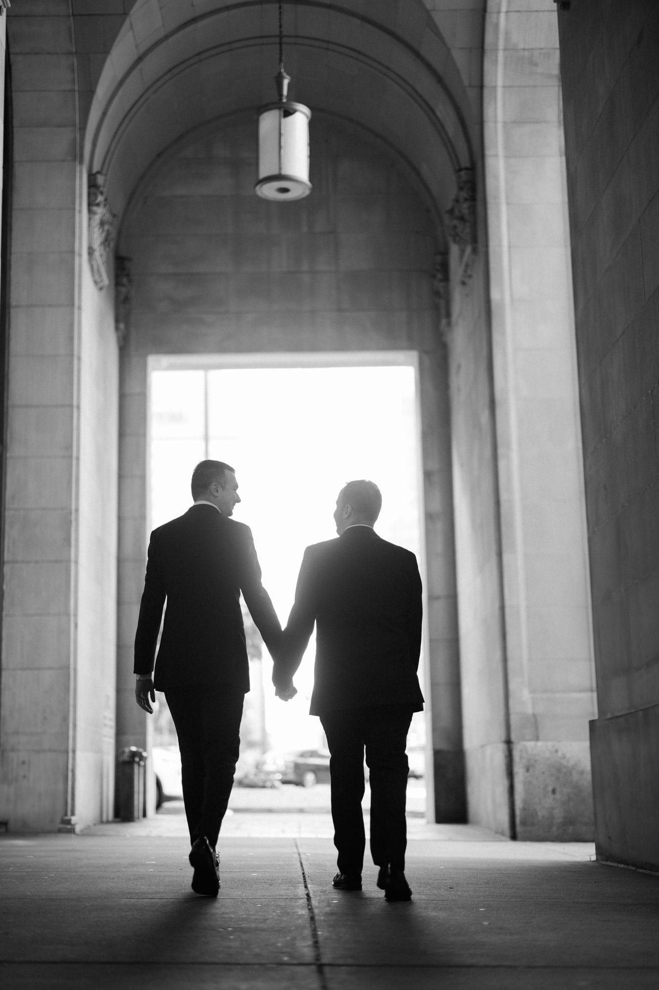 Couple silhouetted walking toward the light through the arched colonnade at The Notary Hotel