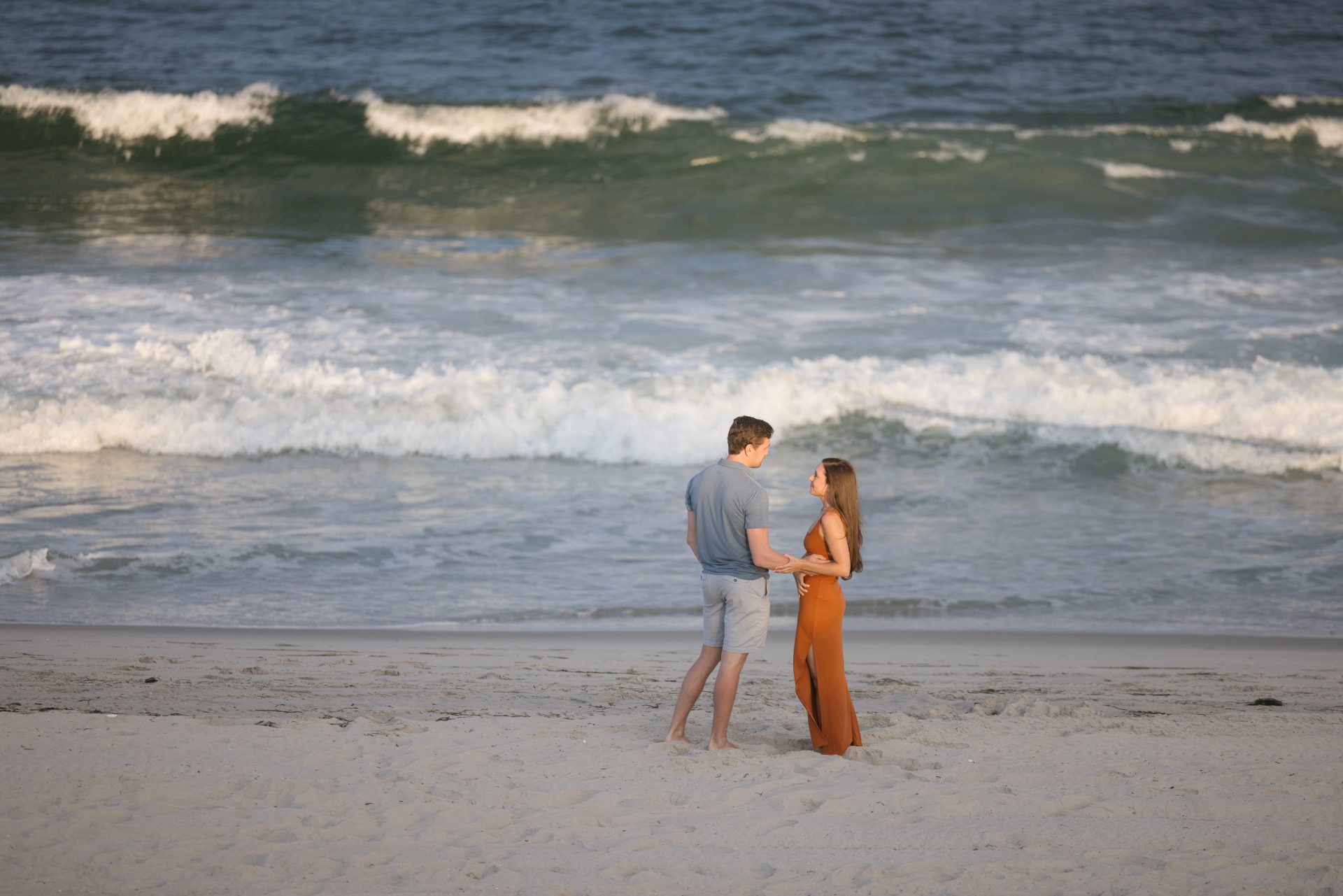 Couple walking along the shoreline on Long Beach Island beach during golden hour