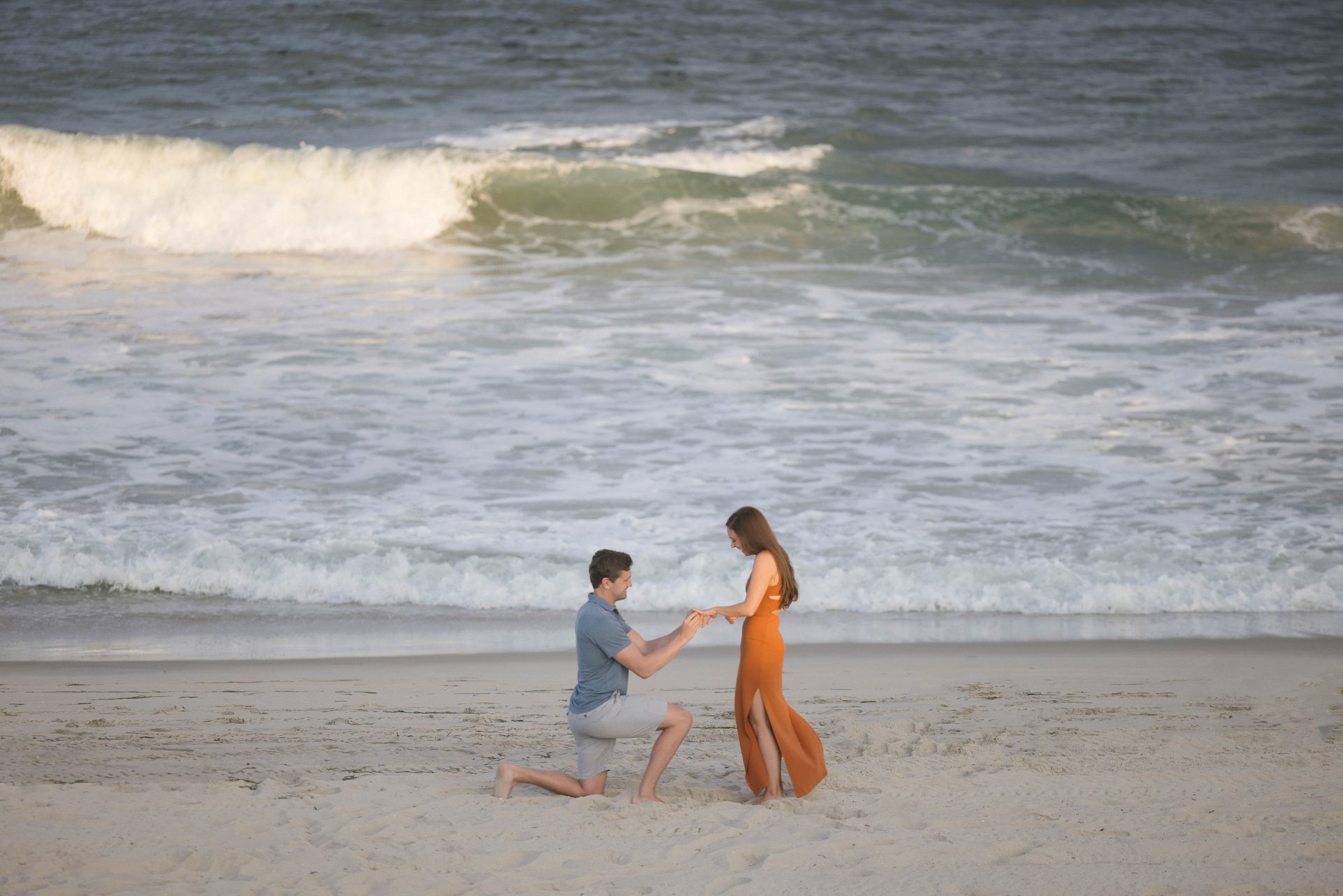 Groom presenting engagement ring during surprise beach proposal on the Jersey Shore, Long Beach Island