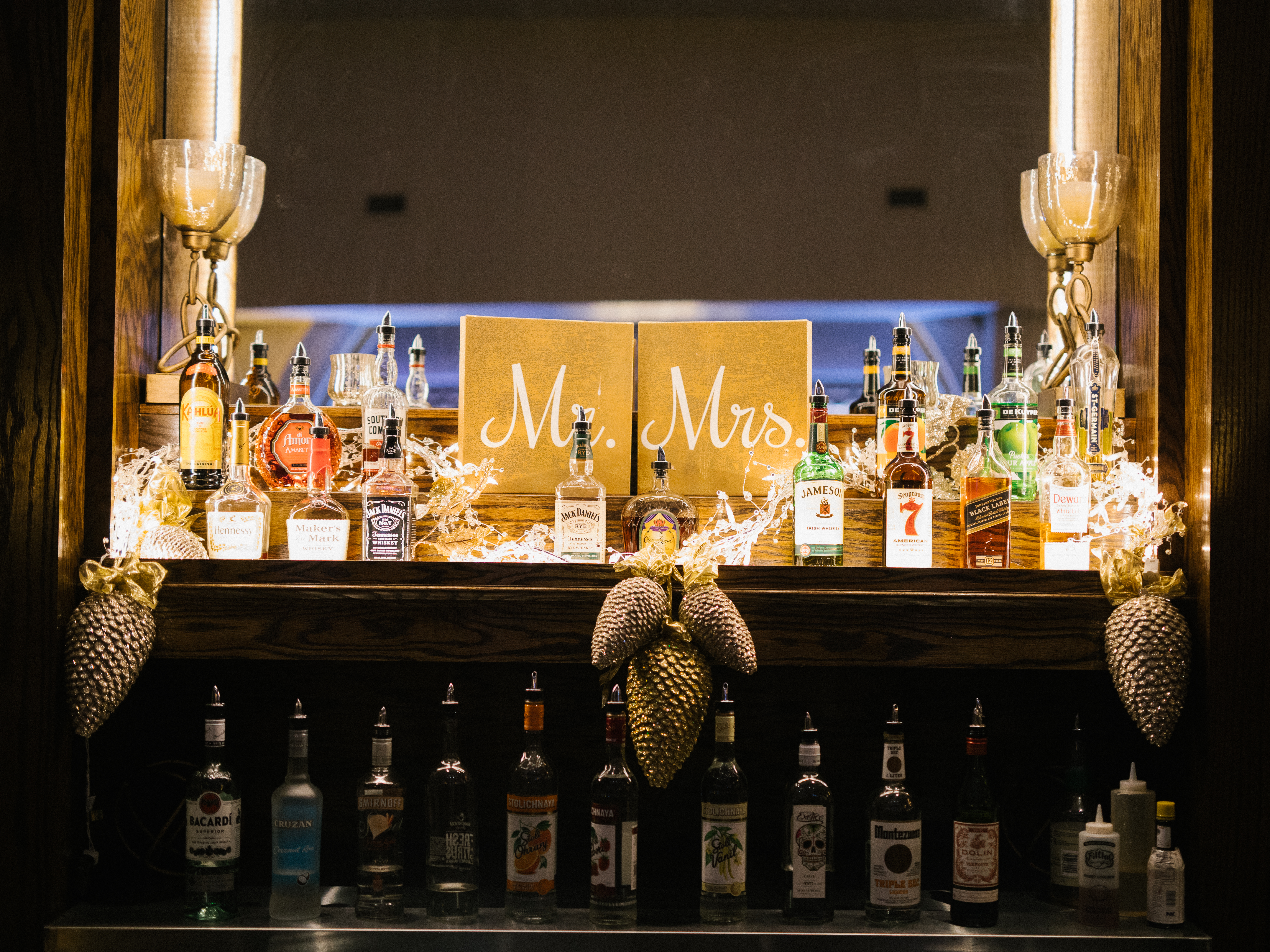 Custom Mr. and Mrs. bar at the Ballroom at the Ben in Philadelphia, with warm lighting and gold pinecone accents, photographed by Jordan Brian