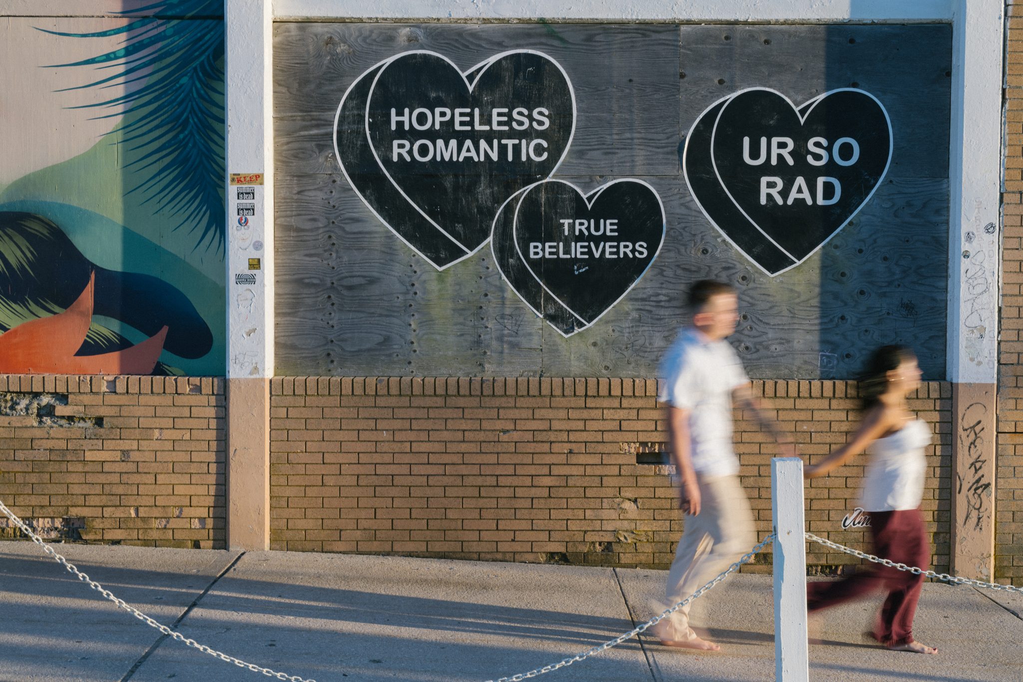 Couple walking past the Hopeless Romantic mural on the Asbury Park boardwalk