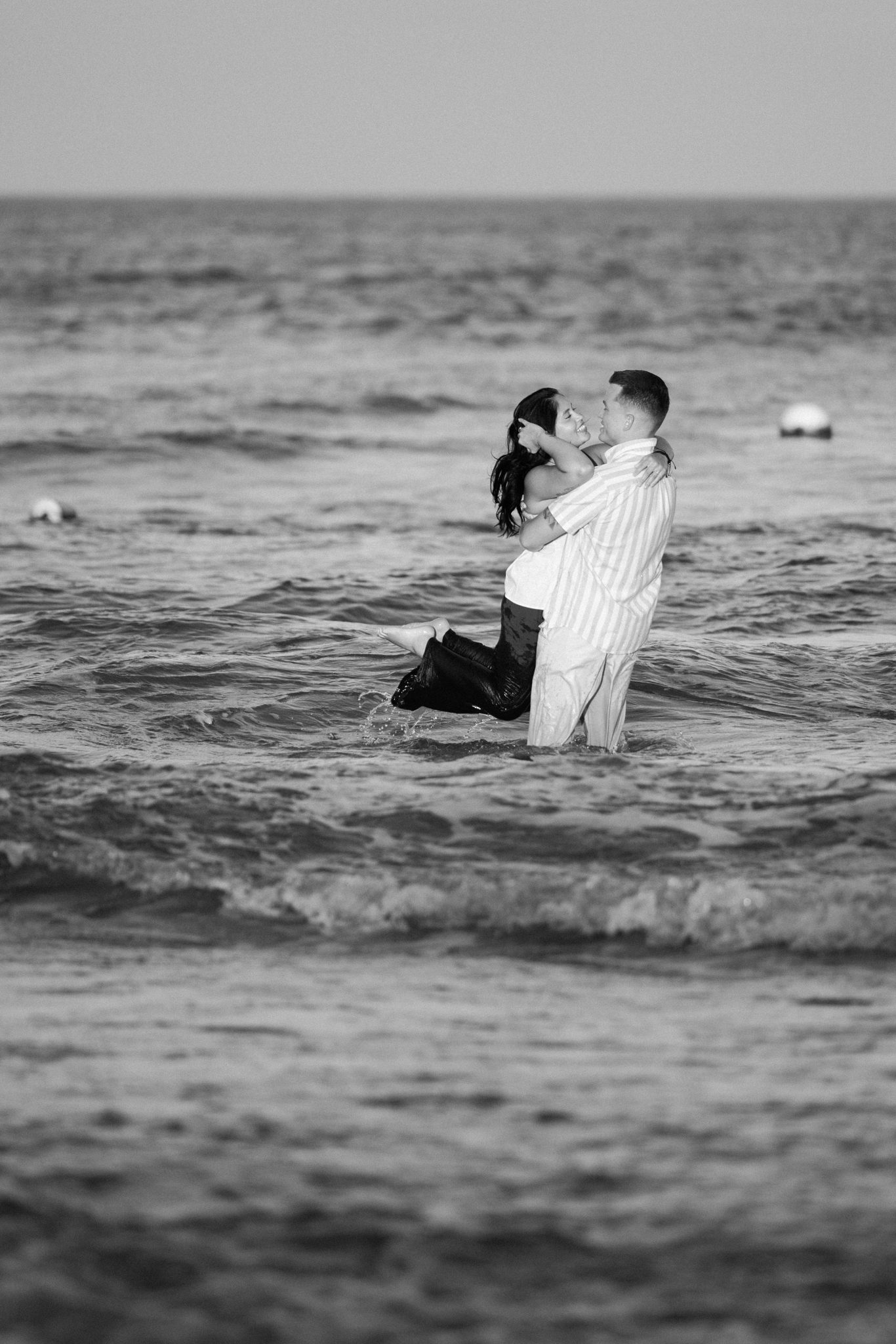 Couple playing in the waves after their Asbury Park proposal