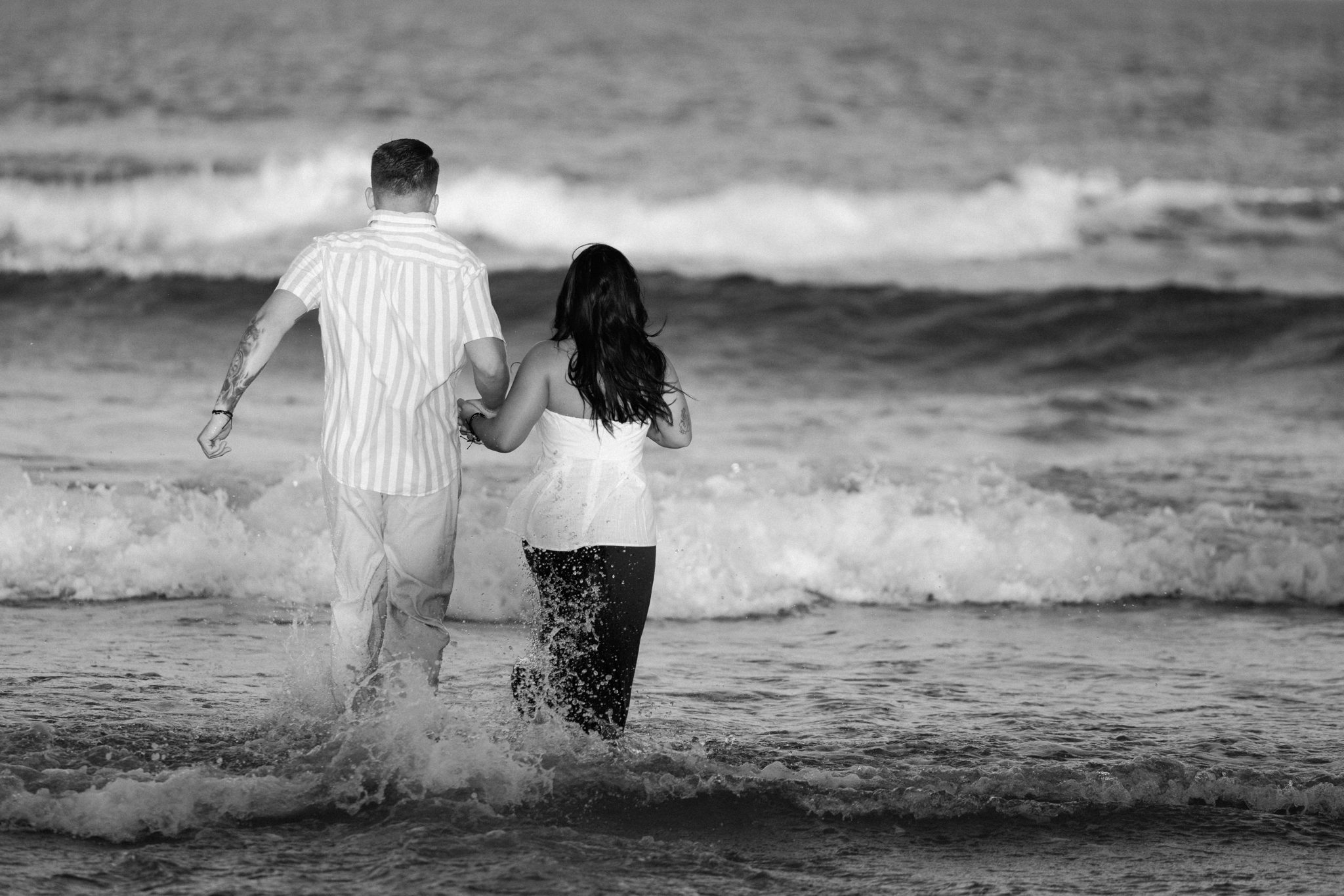 Newly engaged couple walking into the ocean in Asbury Park NJ