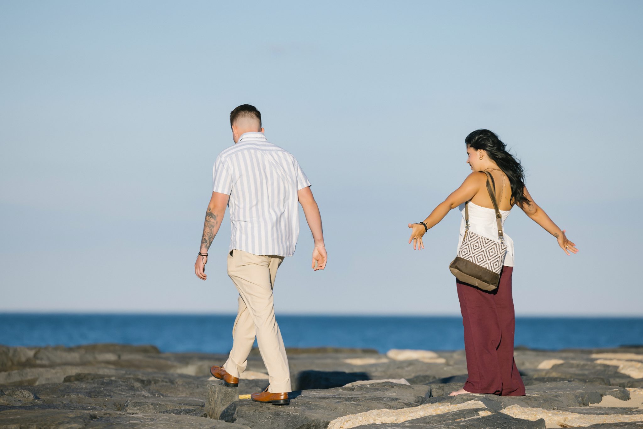 Couple walking on the jetty rocks in Asbury Park NJ at golden hour