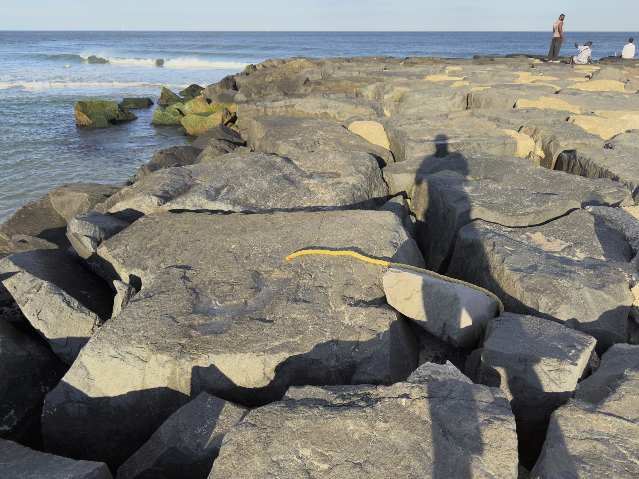 Behind the scenes reference photograph of the yellow rope marking the jetty rock at golden hour in Asbury Park