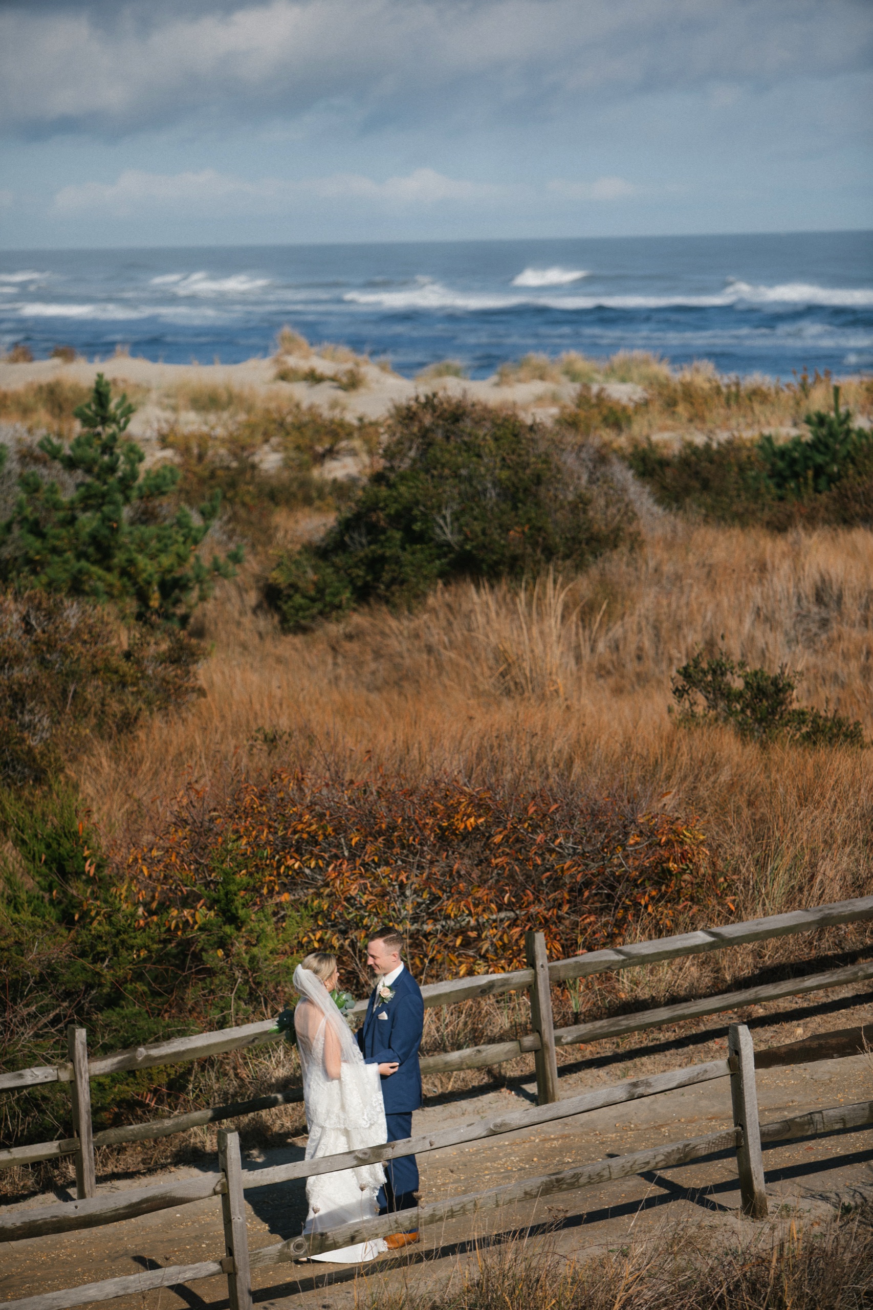 Elevated view of bride and groom during their first look at the ICONA Avalon dune crossing with the ocean behind them, Avalon NJ