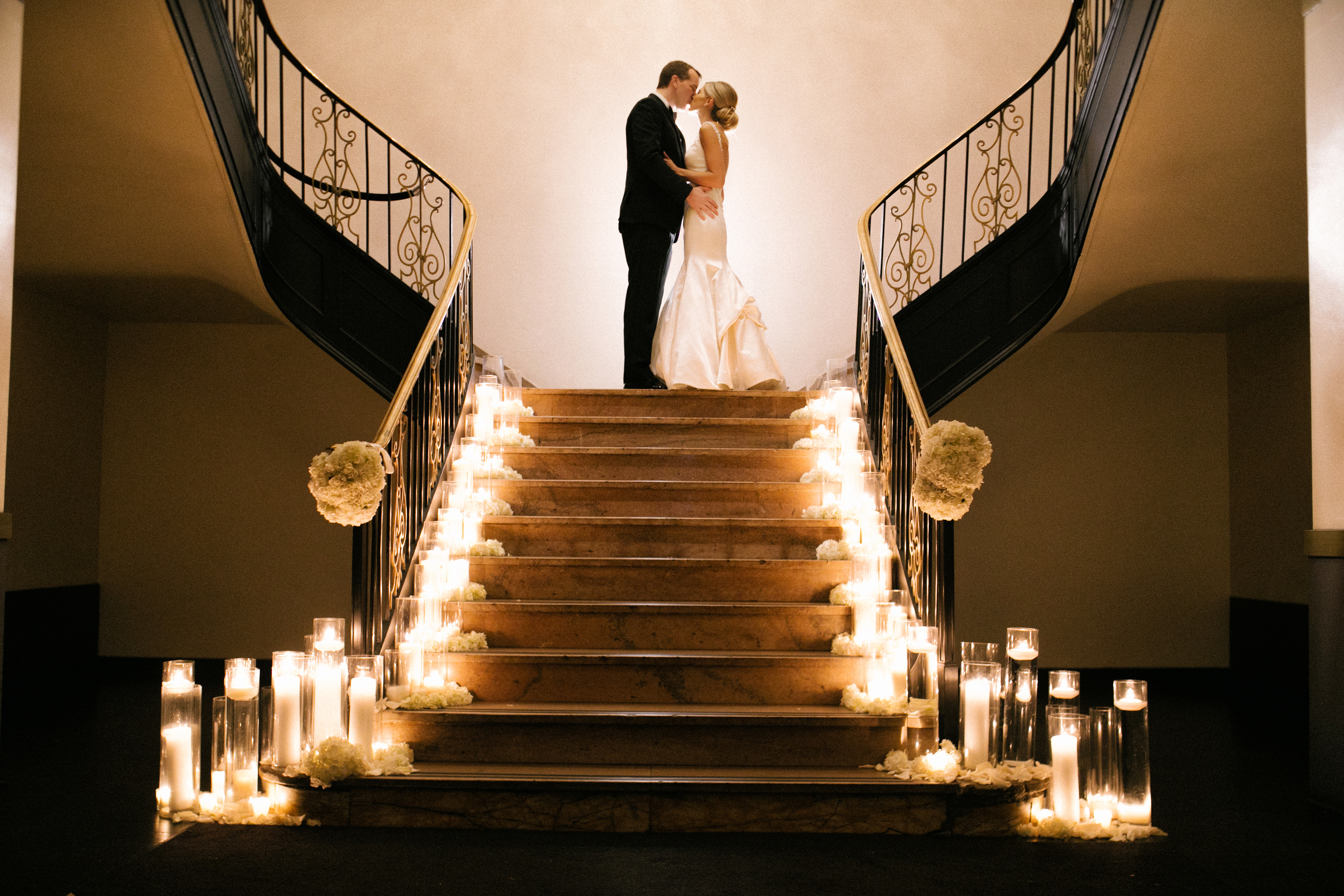 Bride and groom at the top of the grand staircase at the Ballroom at the Ben, with candles lining both sides of the steps, photographed by Jordan Brian