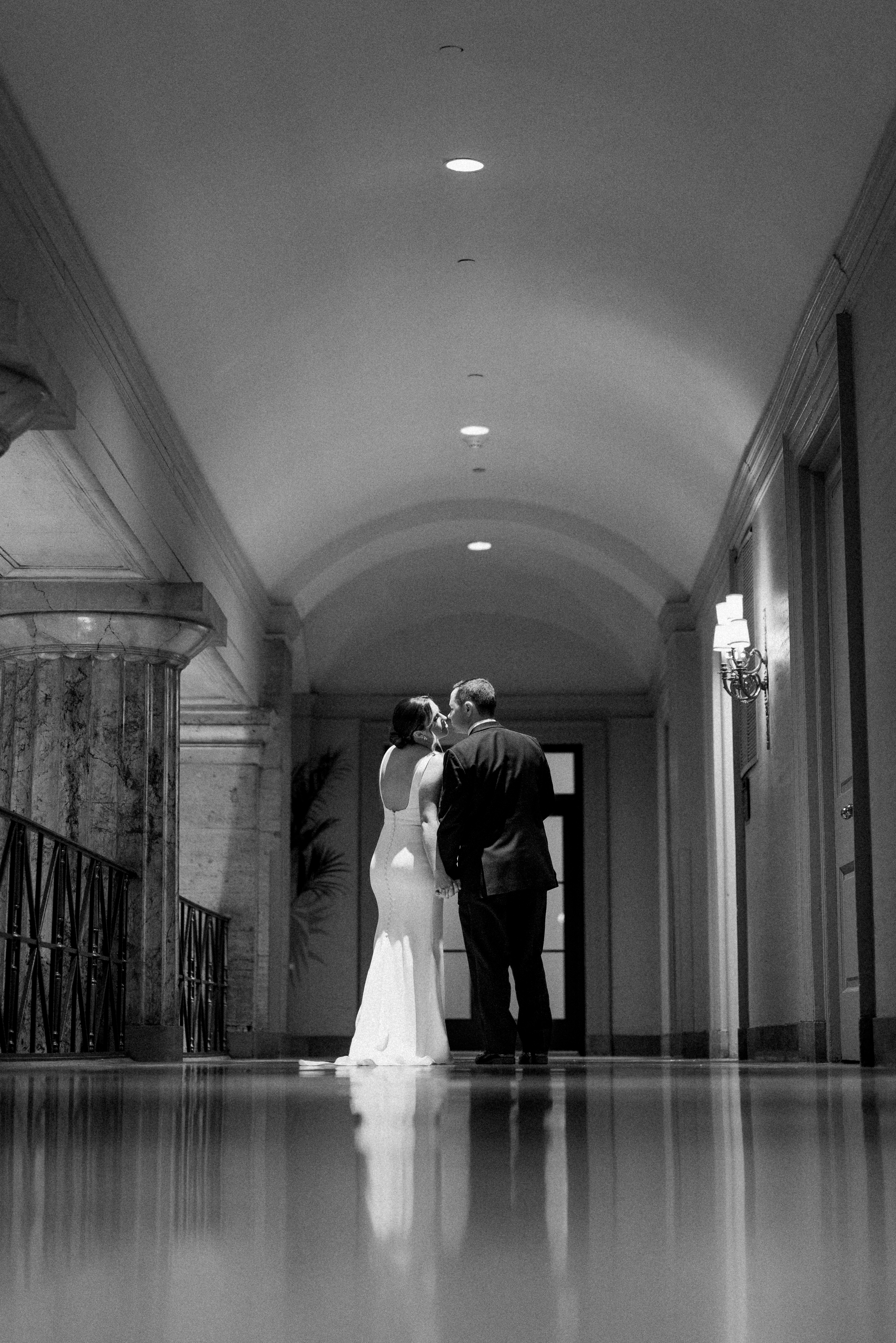 Bride and groom in the long vaulted hallway leading out to the outdoor balcony at the Ballroom at the Ben in Philadelphia, arched ceiling and reflective floor, photographed by Jordan Brian