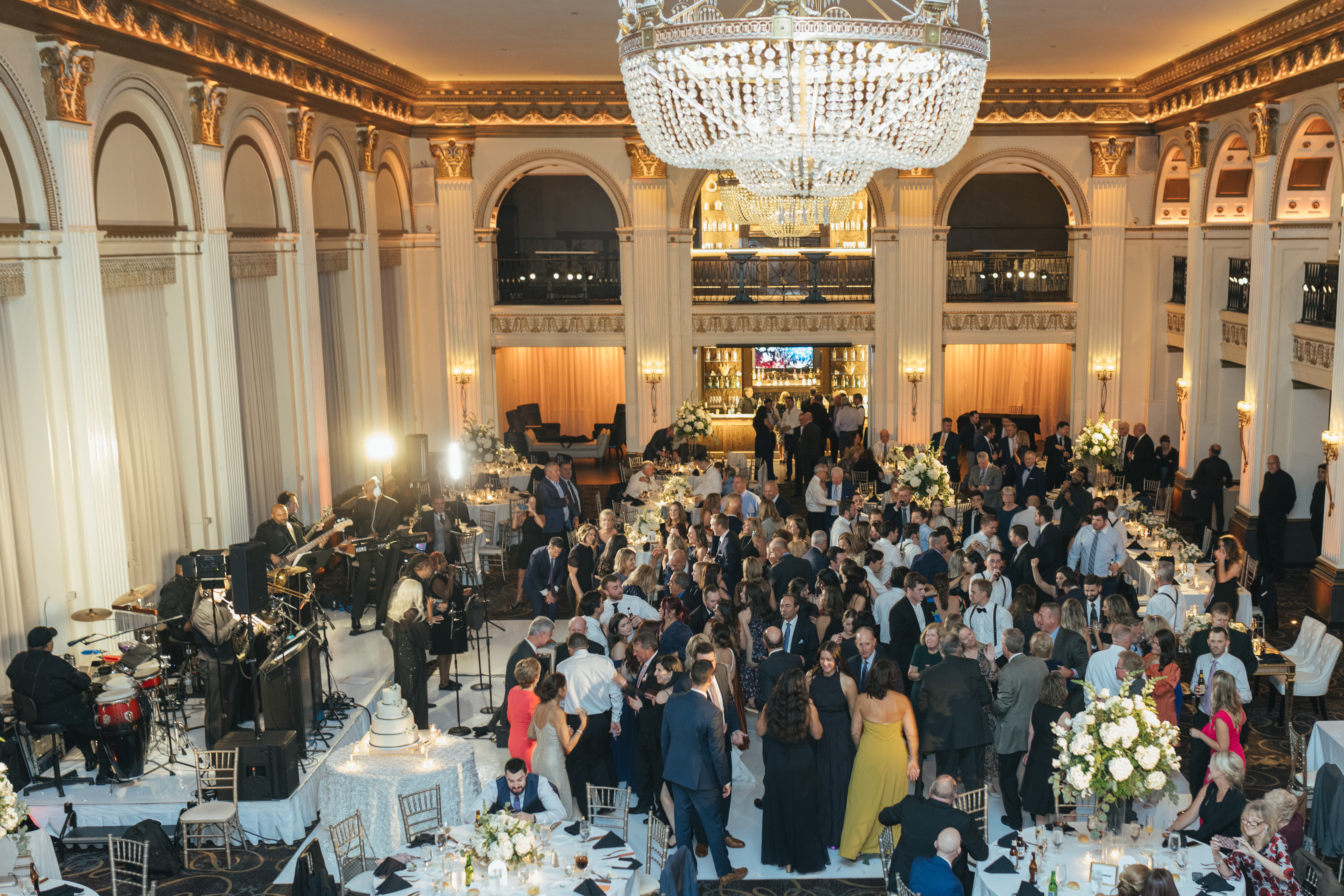 Packed dance floor under the chandelier at the Ballroom at the Ben, with the live band playing and guests filling the white dance floor, photographed by Jordan Brian