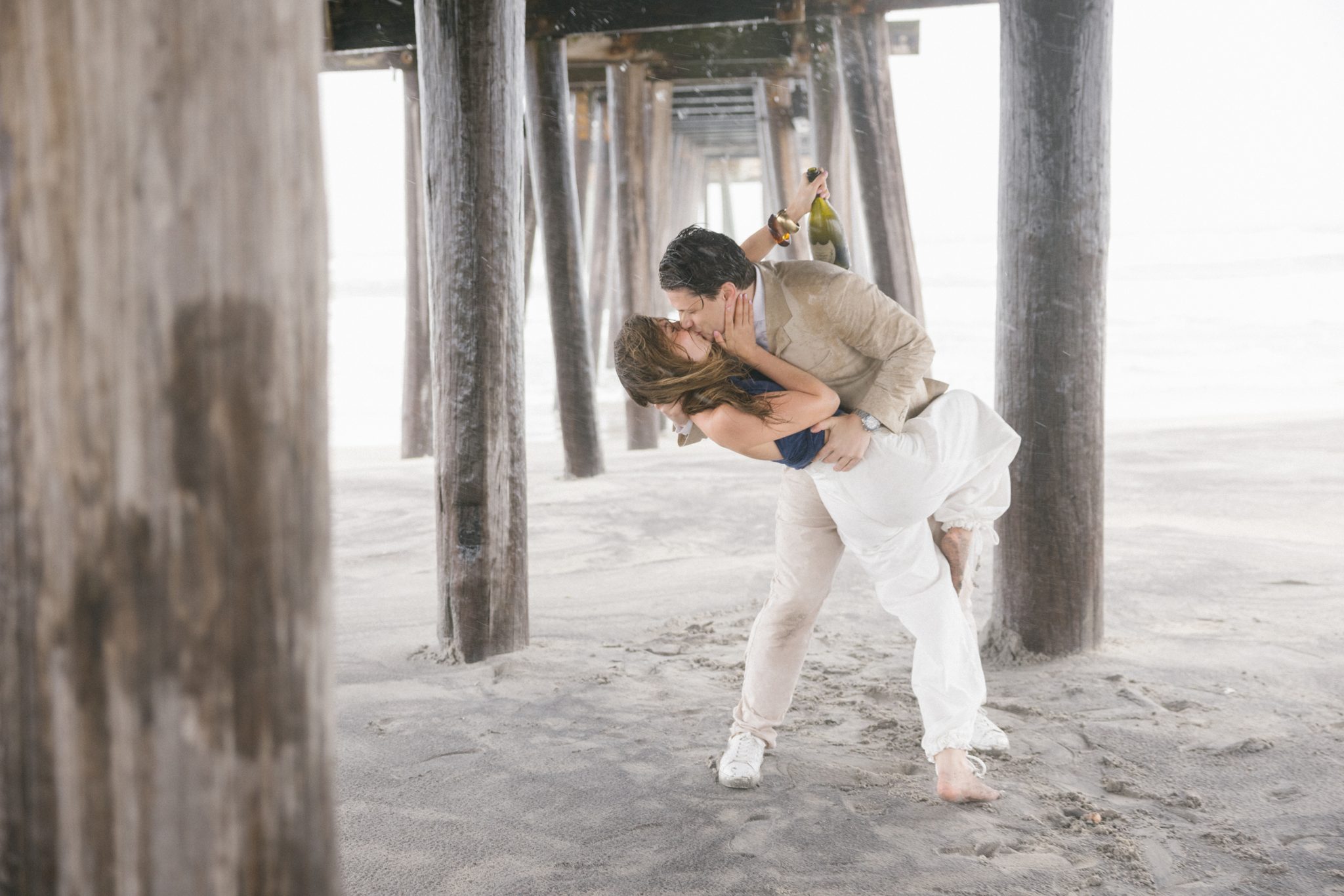 Couple sharing a dip kiss in the rain at their Ocean City NJ beach proposal