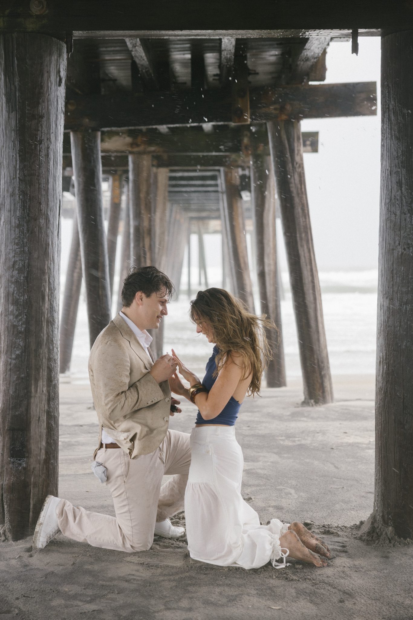 Newly engaged woman looking at her engagement ring under the pier in Ocean City NJ