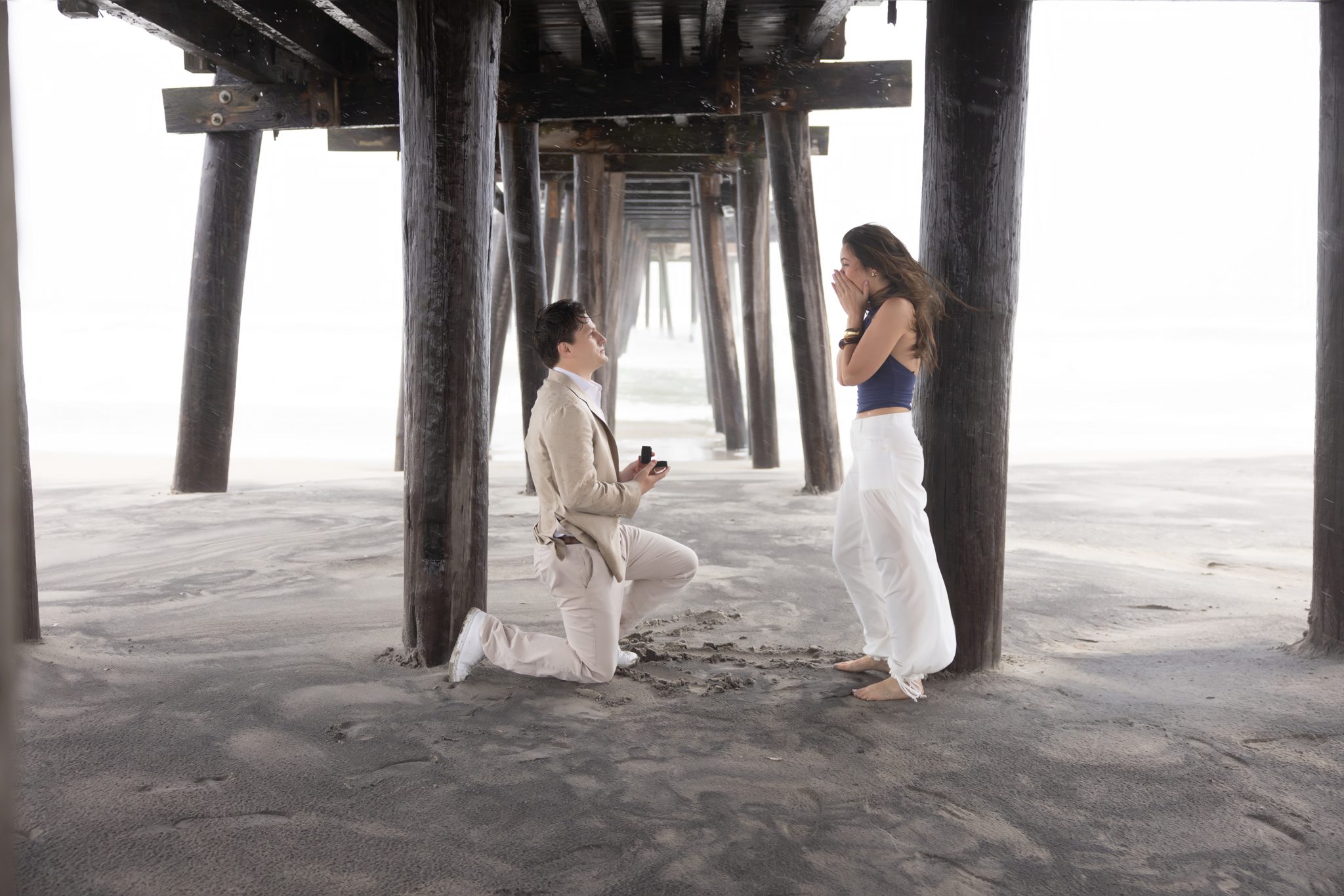 Man kneeling to propose under the 14th Street Fishing Pier in Ocean City NJ