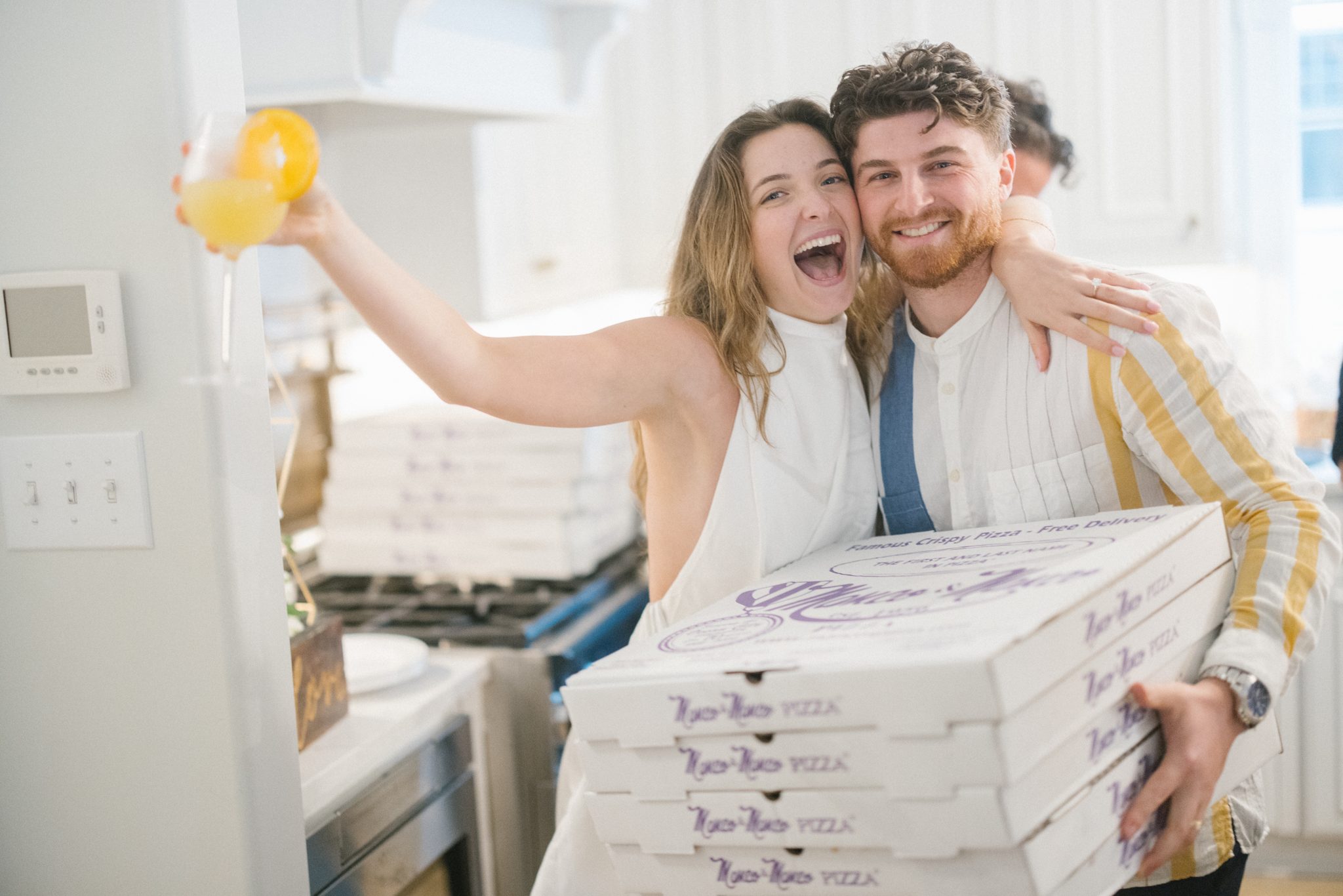 Newly engaged couple holding Manco and Manco pizza boxes at their engagement party