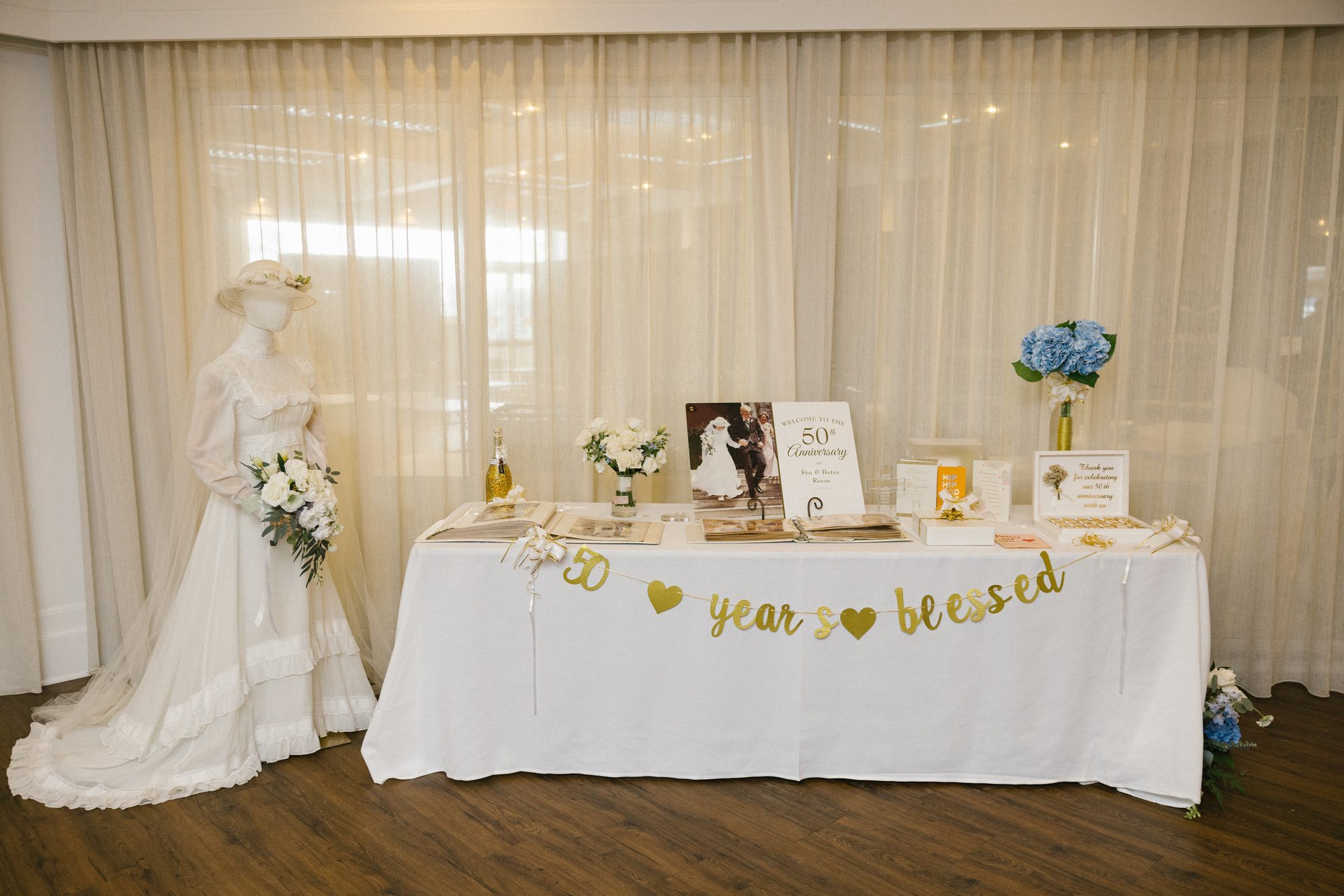 A fifty years blessed anniversary table with a lace wedding gown and a framed wedding photo at a 50th celebration