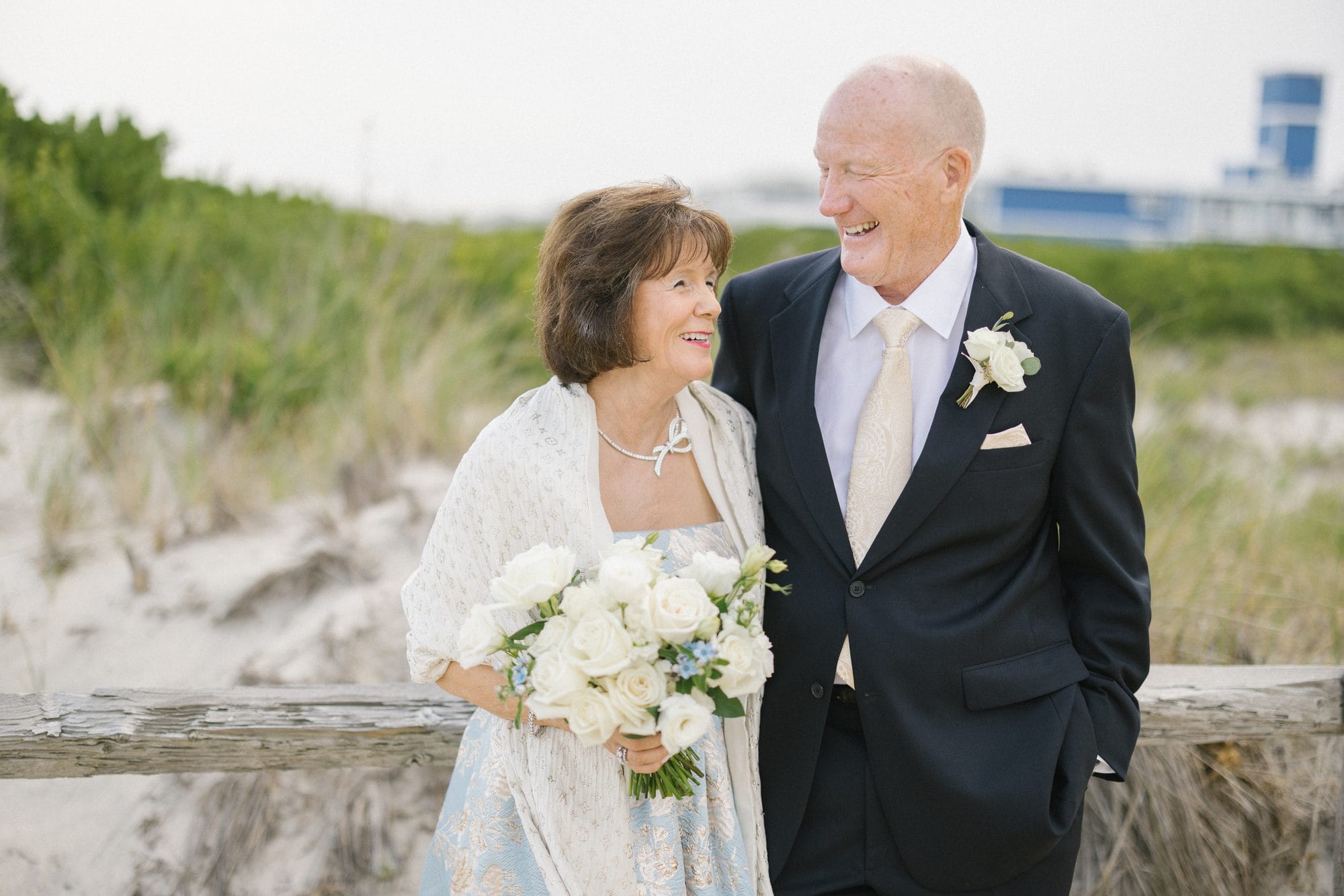 Stu and Betsy laughing together on the beach at their 50th anniversary vow renewal in Avalon, New Jersey