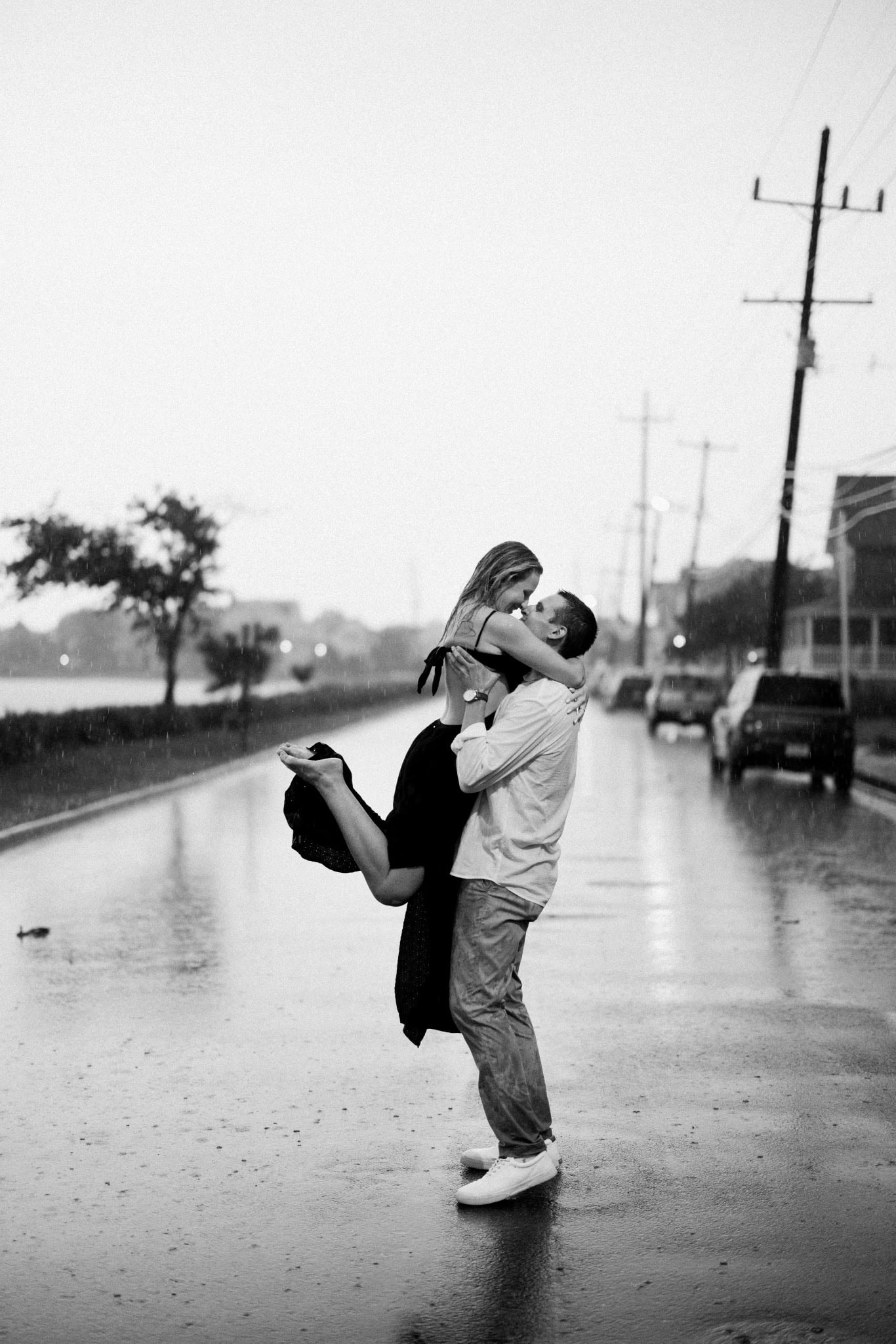 Black and white photo of a groom lifting his fiancee in the rain on a Bay Head NJ street