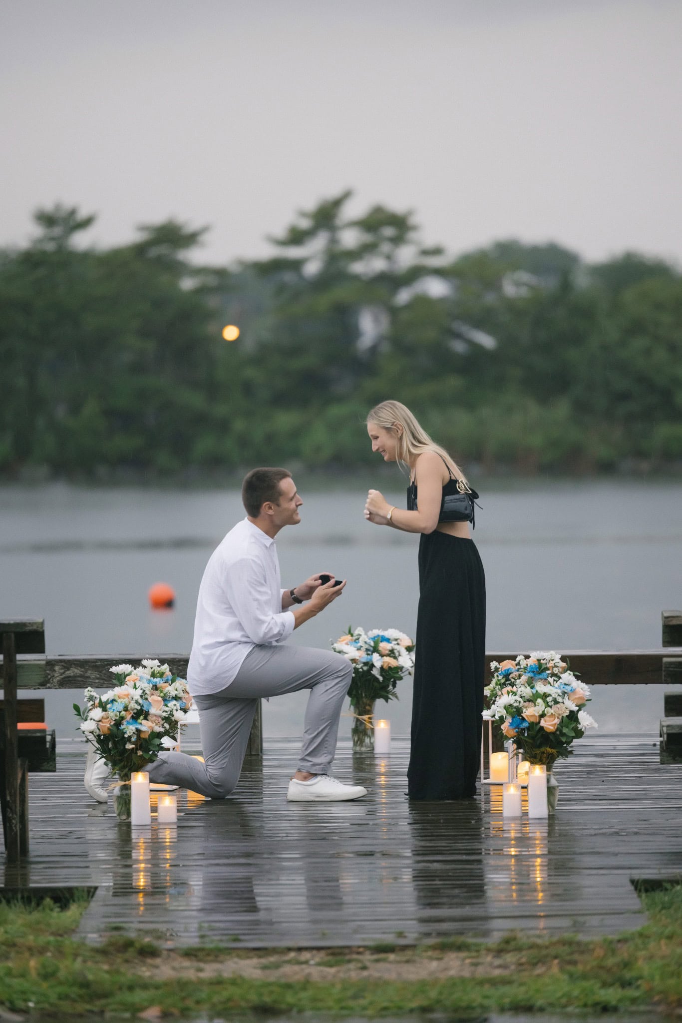 Man down on one knee proposing with a ring on a candlelit Twilight Lake dock in Bay Head NJ
