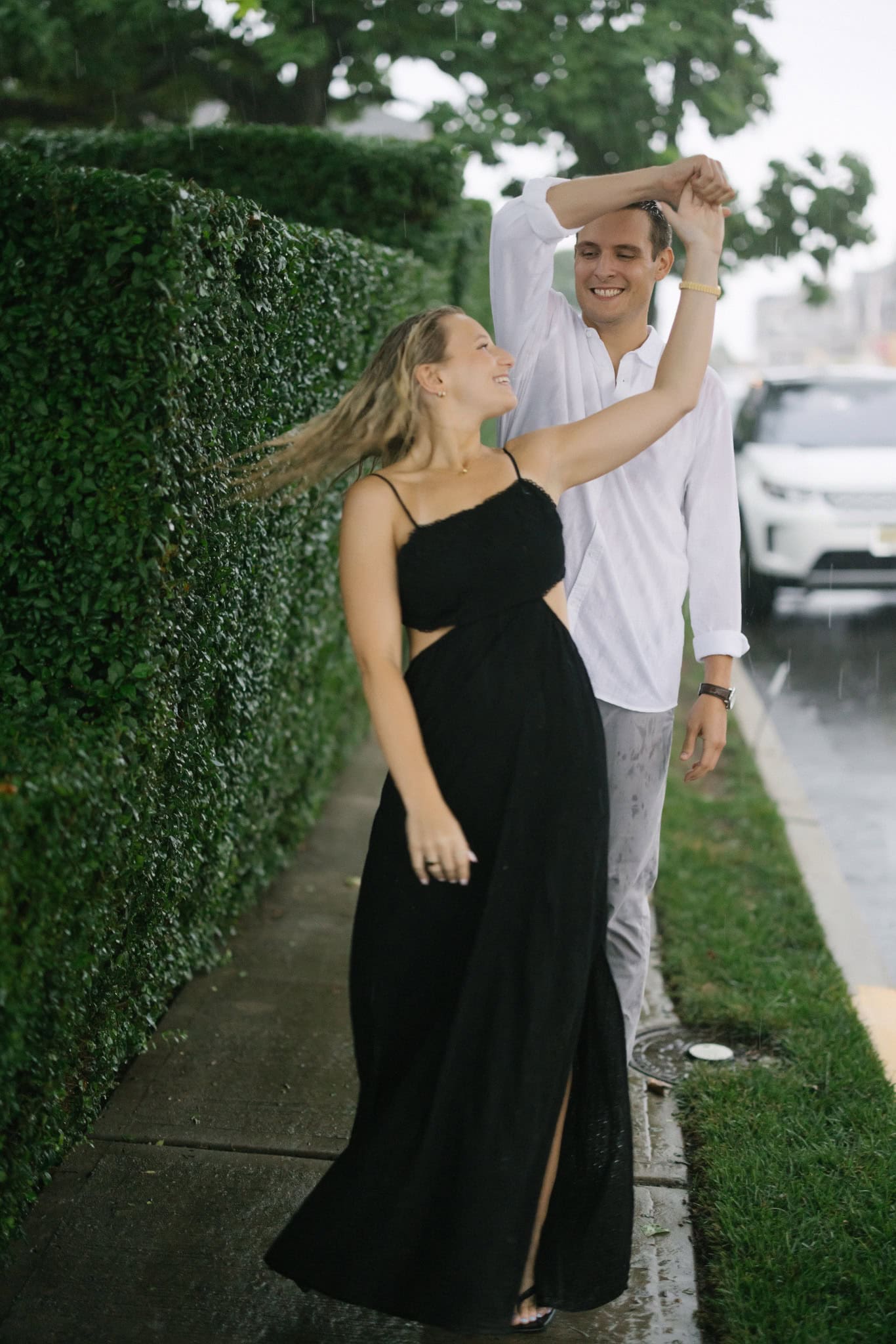 Groom twirling his fiancee dancing in the rain on a Bay Head NJ street