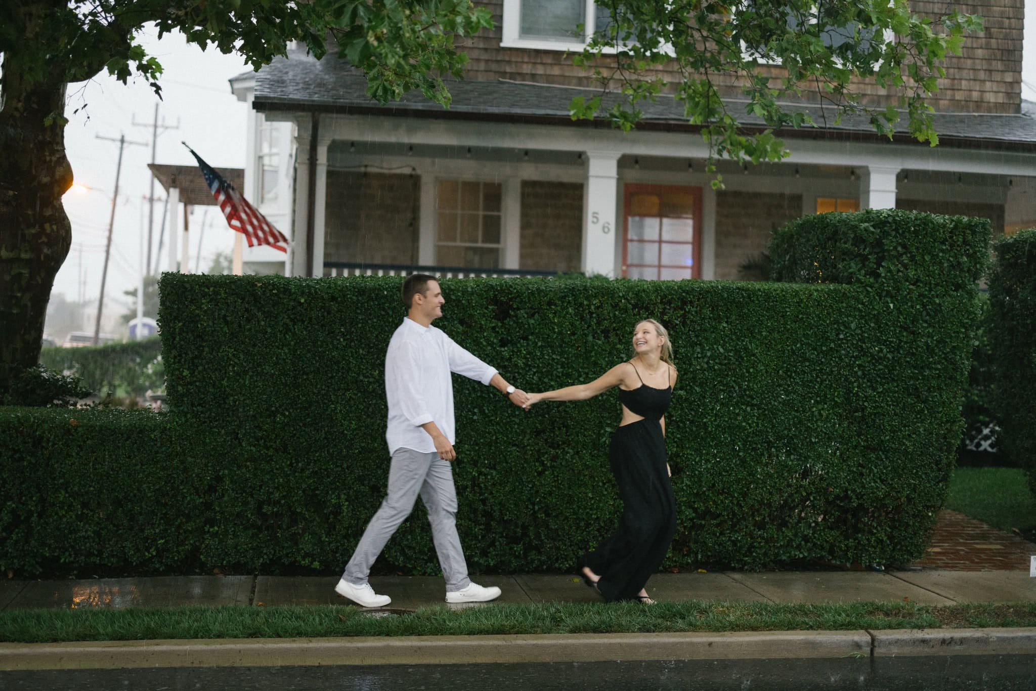 Engaged couple holding hands and playing in the rain on a Bay Head NJ street