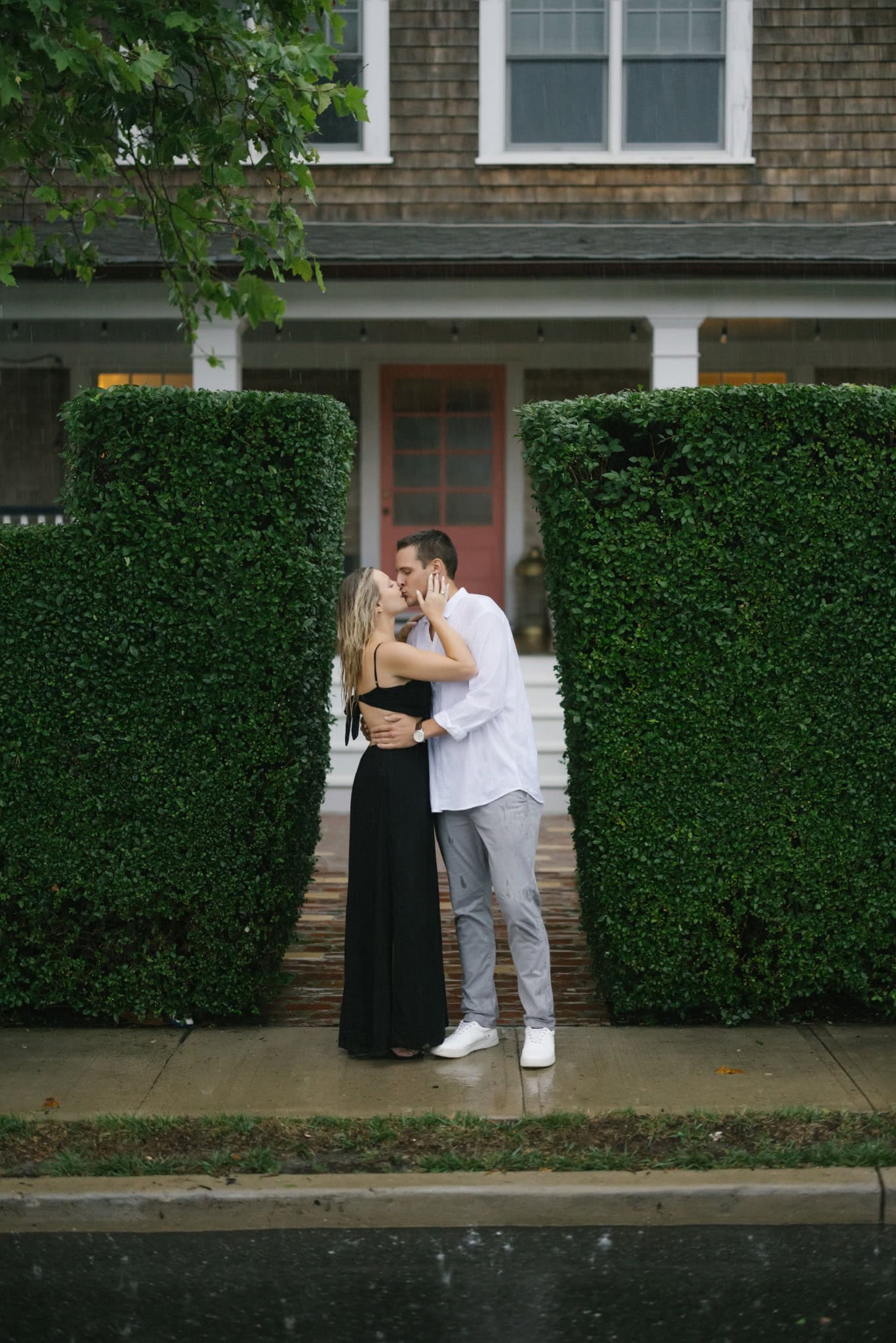 Newly engaged couple embracing in front of a shingled shore house in Bay Head NJ