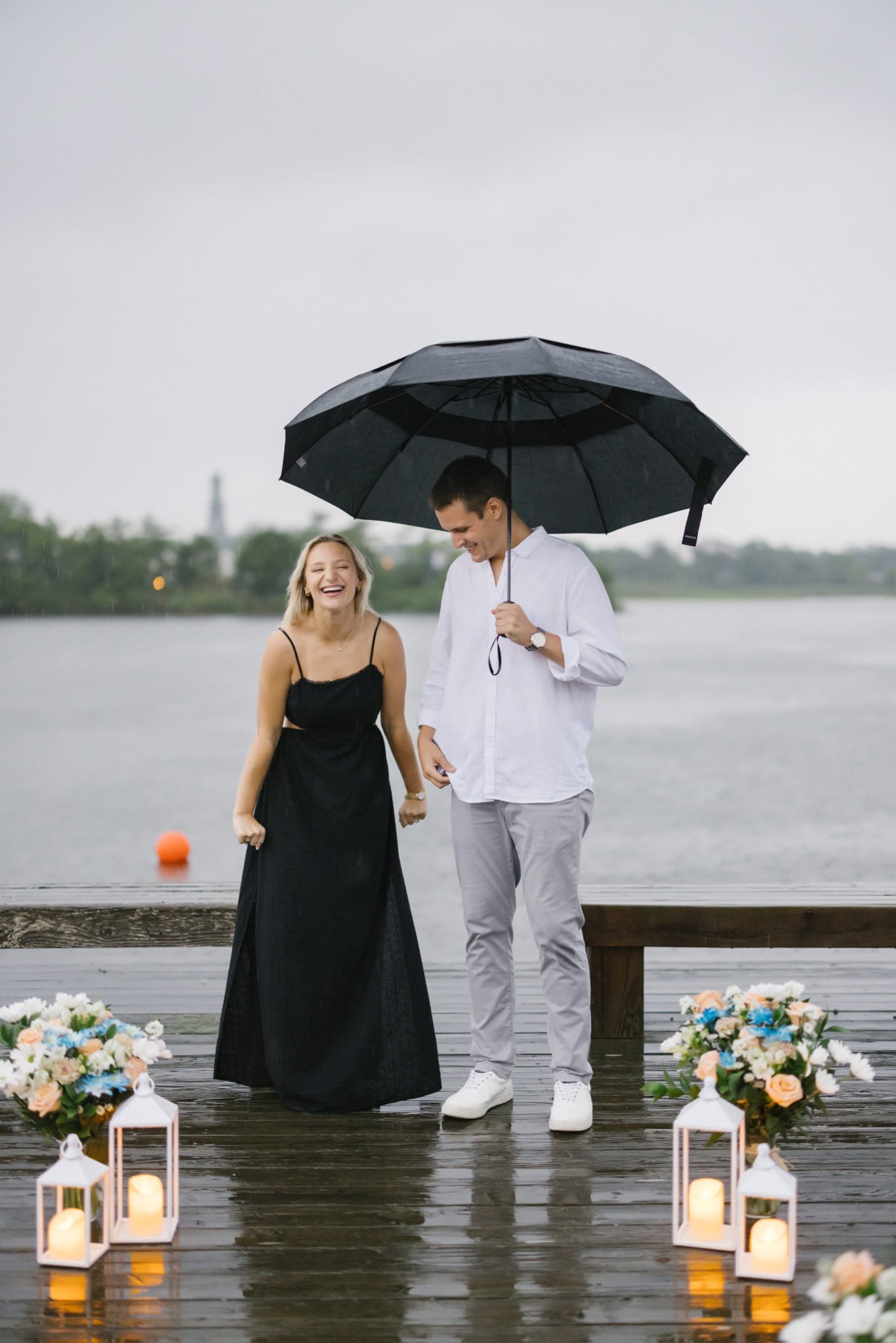 Couple walking a lantern lined dock under storm clouds on Twilight Lake in Bay Head NJ