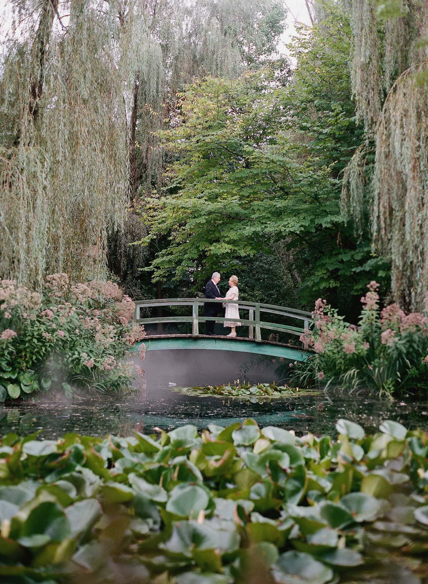 A couple standing on the Monet bridge over the lily pond at Grounds for Sculpture during their vow renewal