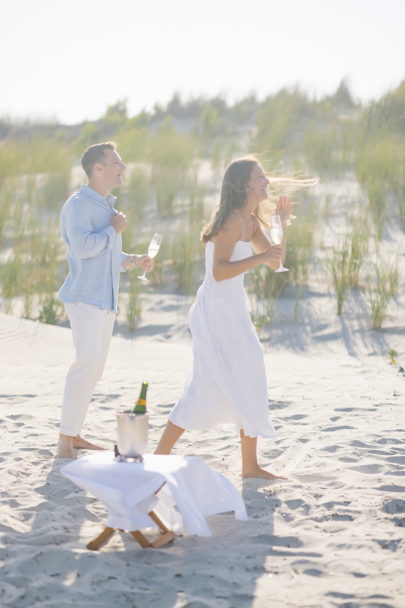 Katie and Chris celebrating with champagne glasses raised on the beach in Stone Harbor, New Jersey