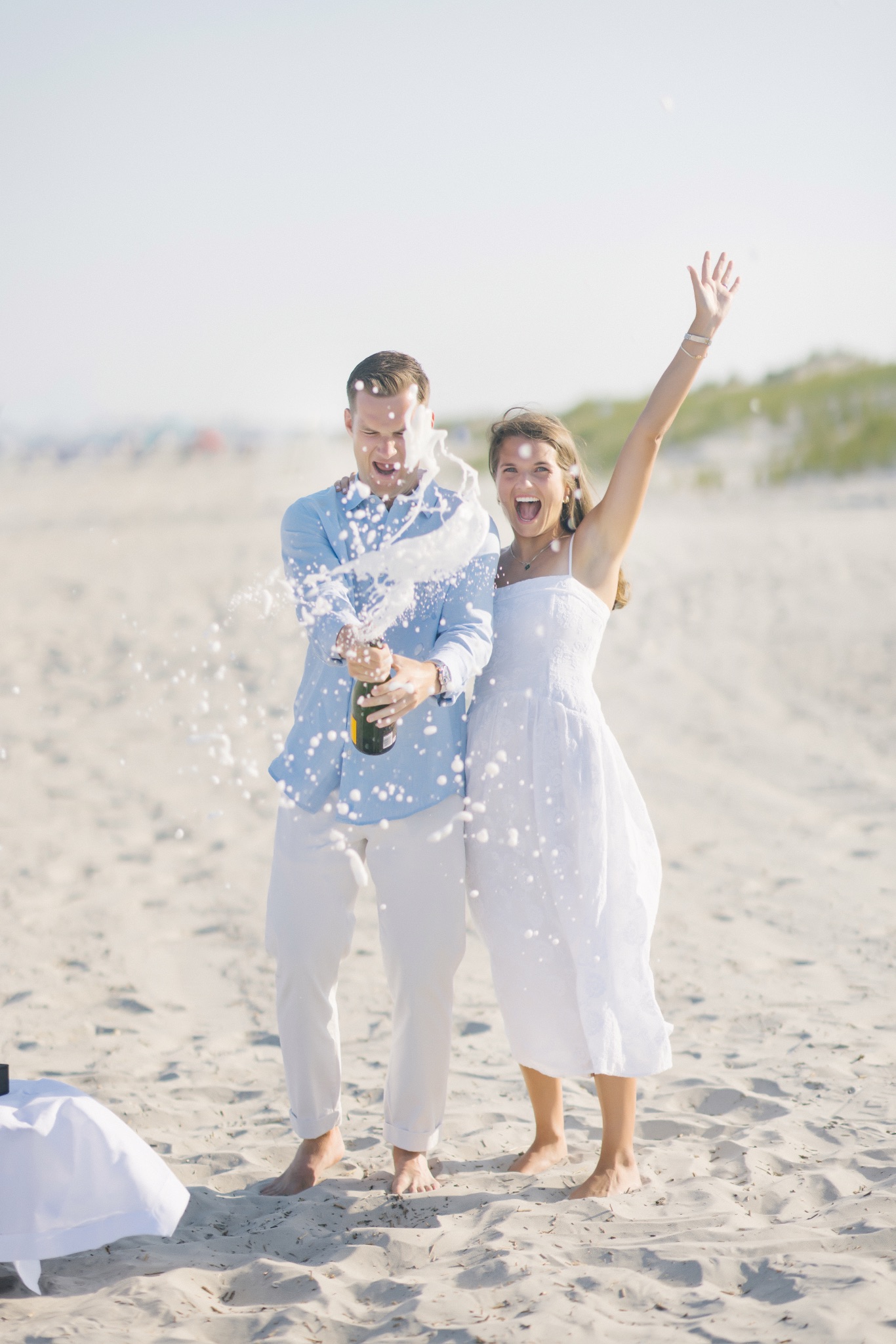 Chris popping the champagne cork to celebrate the engagement on the beach in Stone Harbor, New Jersey