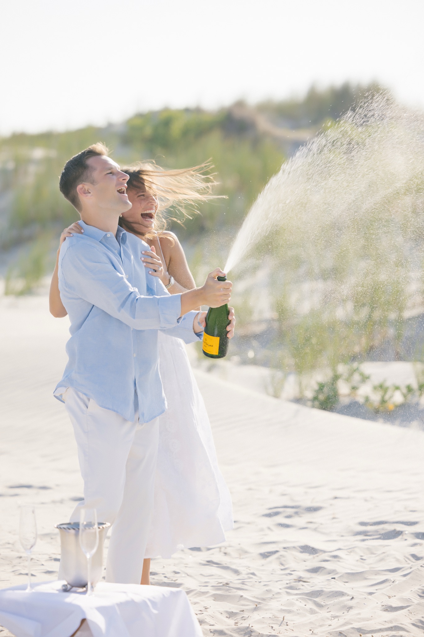 Katie and Chris laughing in the champagne spray on the beach in Stone Harbor, New Jersey