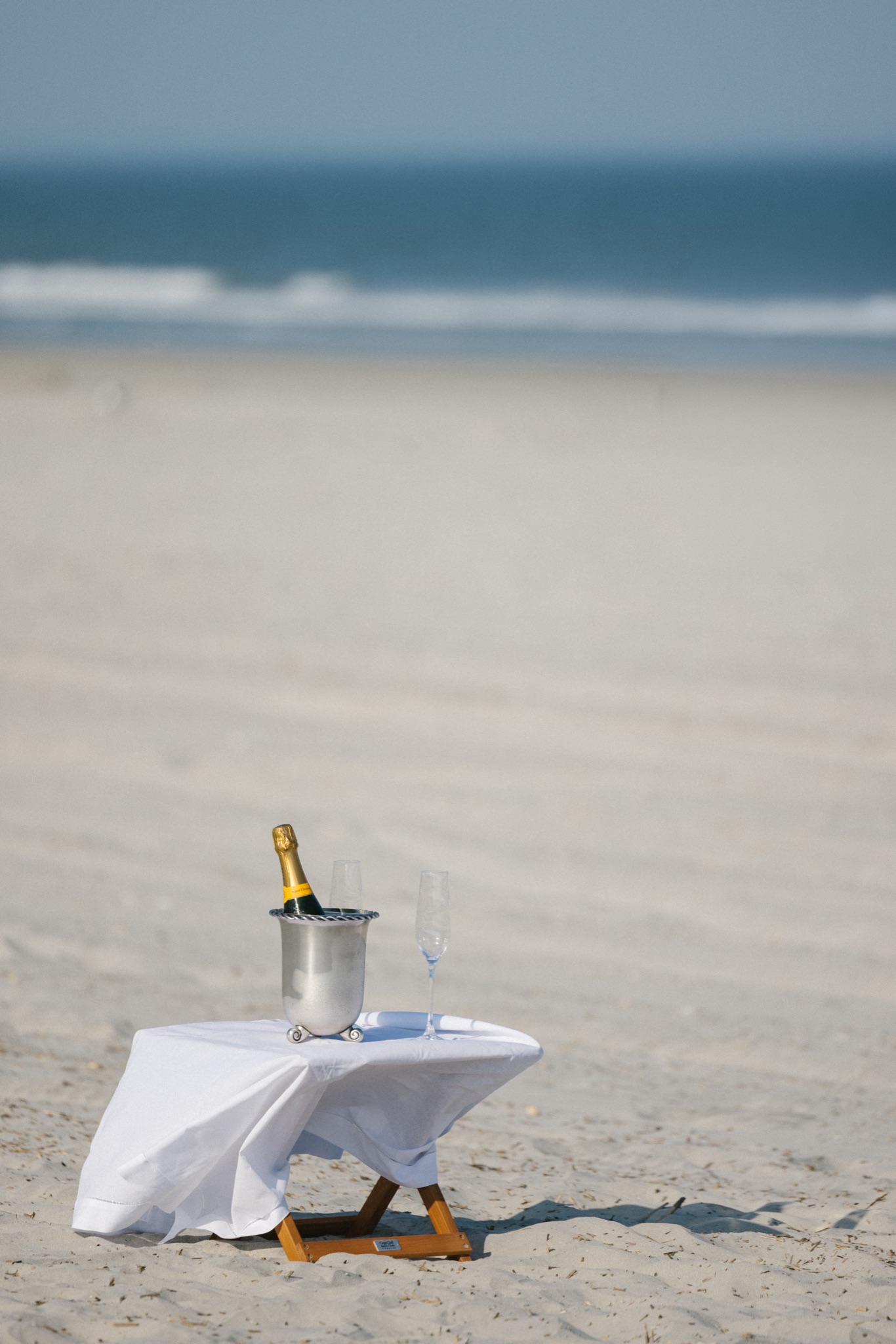 Champagne bottle chilling on a small table with a tablecloth set up on the beach in Stone Harbor, New Jersey