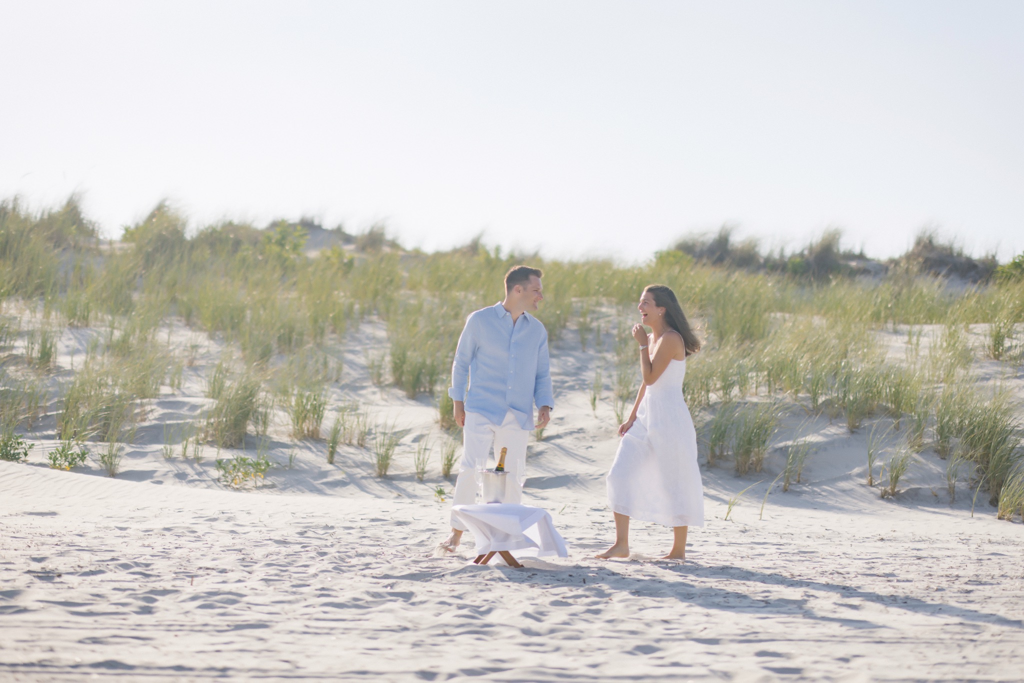 Couple standing on the beach between the dunes in Stone Harbor, New Jersey before a surprise proposal