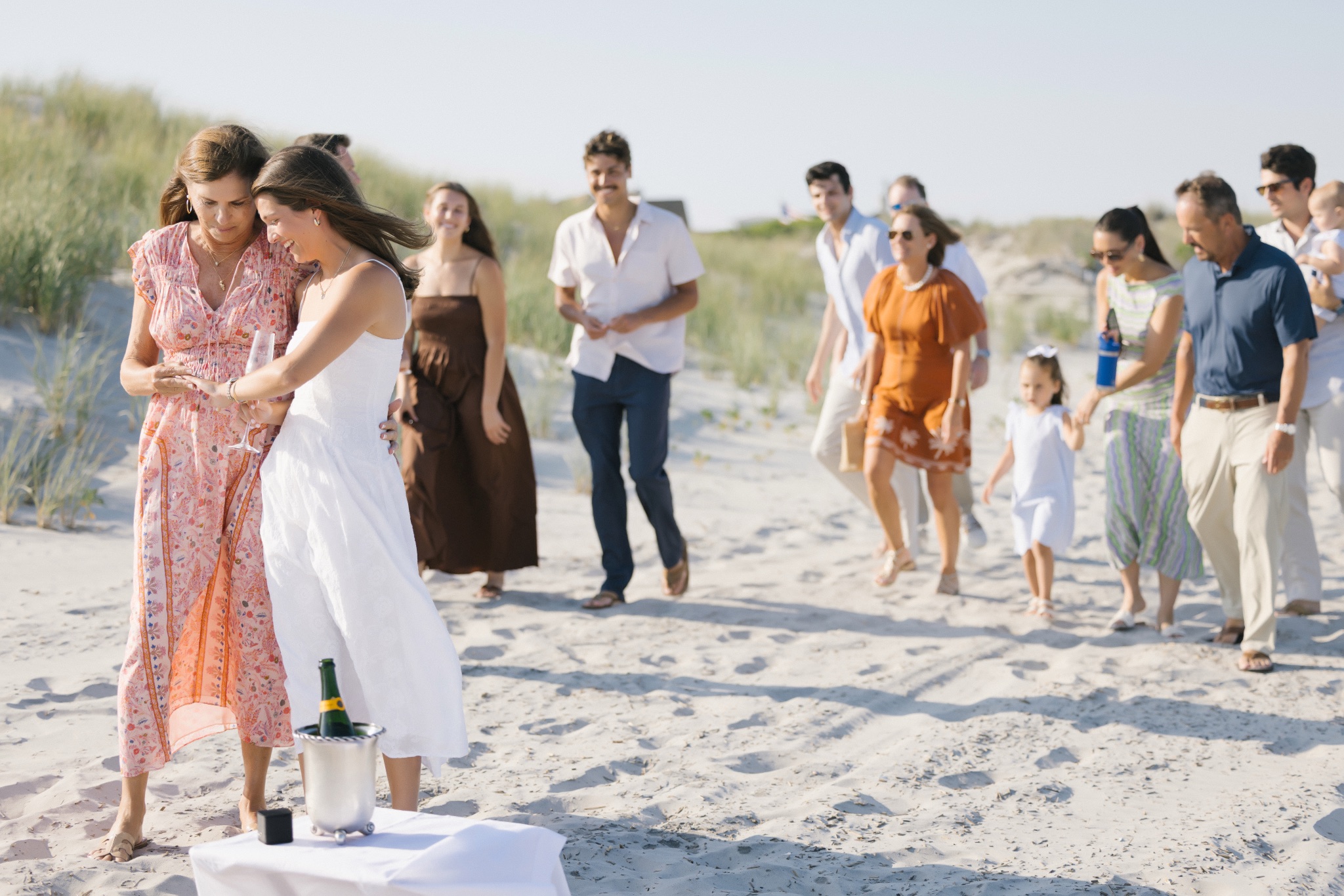 Katie hugging her mom as the rest of the family walks down the beach to surprise the couple in Stone Harbor, New Jersey