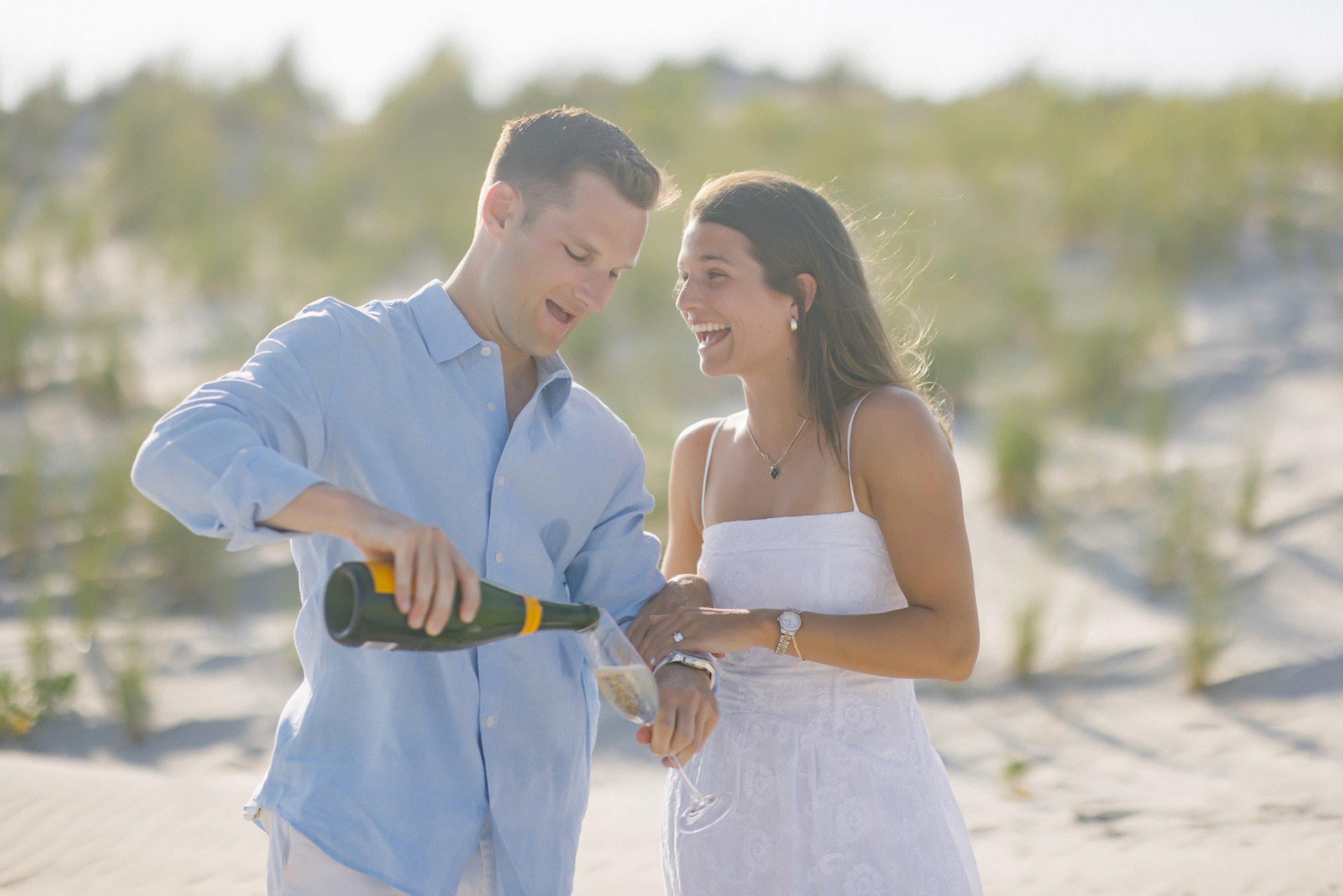 Chris pouring champagne for Katie after the proposal on the beach in Stone Harbor, New Jersey