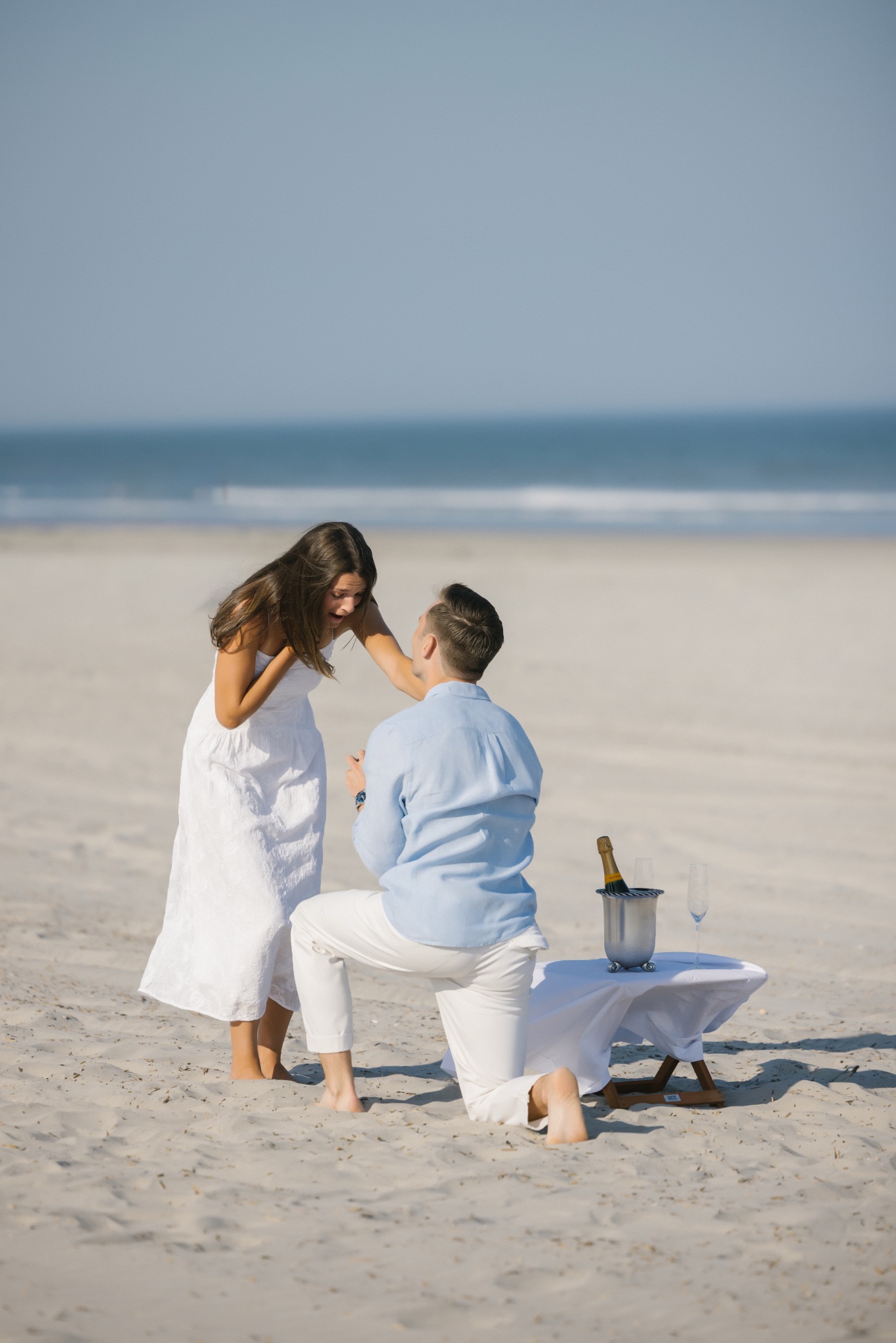 Chris proposing to Katie with the ocean behind them on the beach in Stone Harbor, New Jersey