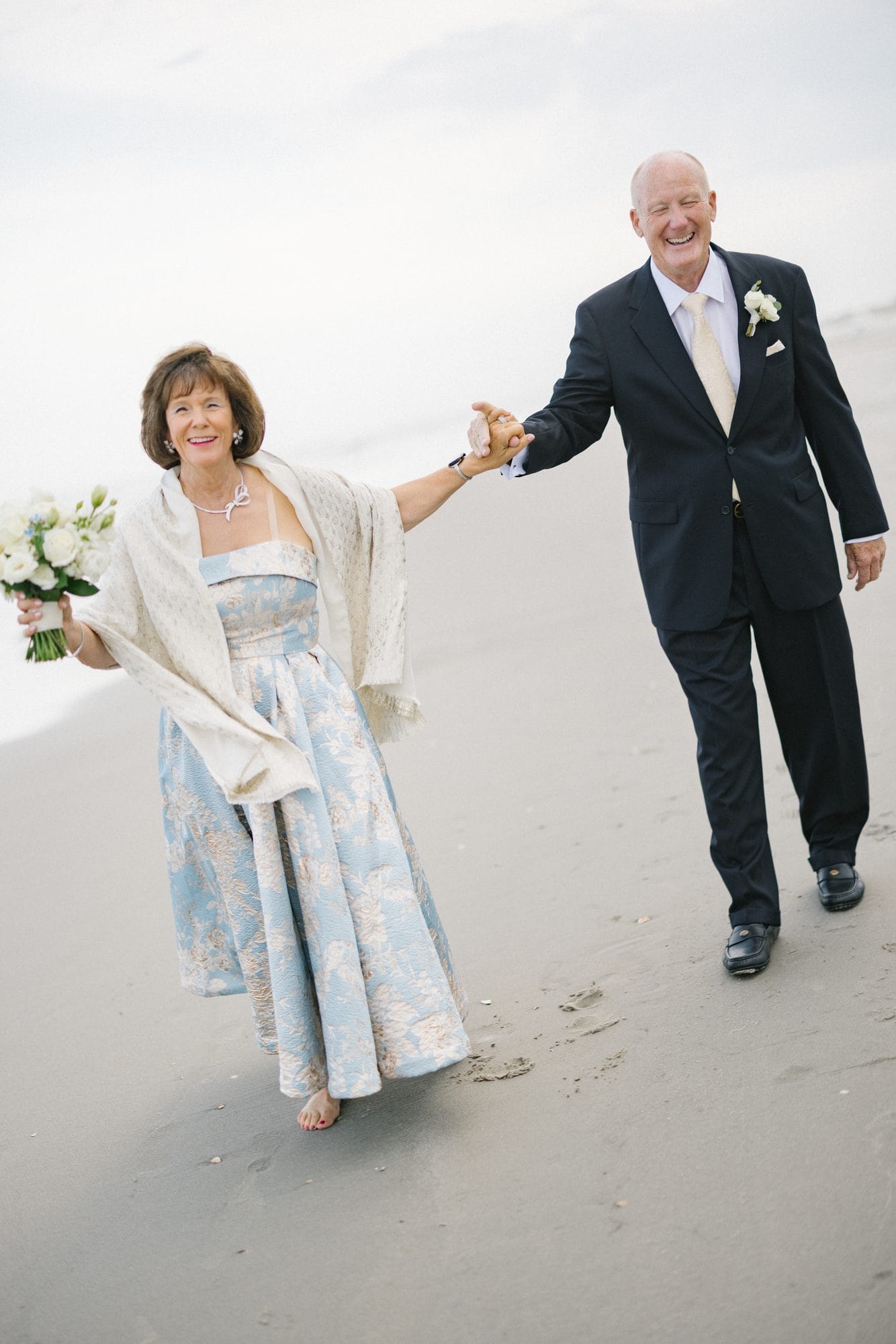 A playful beach portrait of a couple during their 50th anniversary vow renewal in Avalon, New Jersey