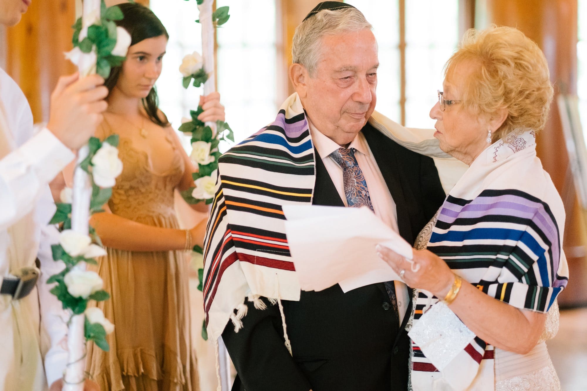 A couple reading their vows under a chuppah with a tallit prayer shawl at their 50th anniversary vow renewal ceremony
