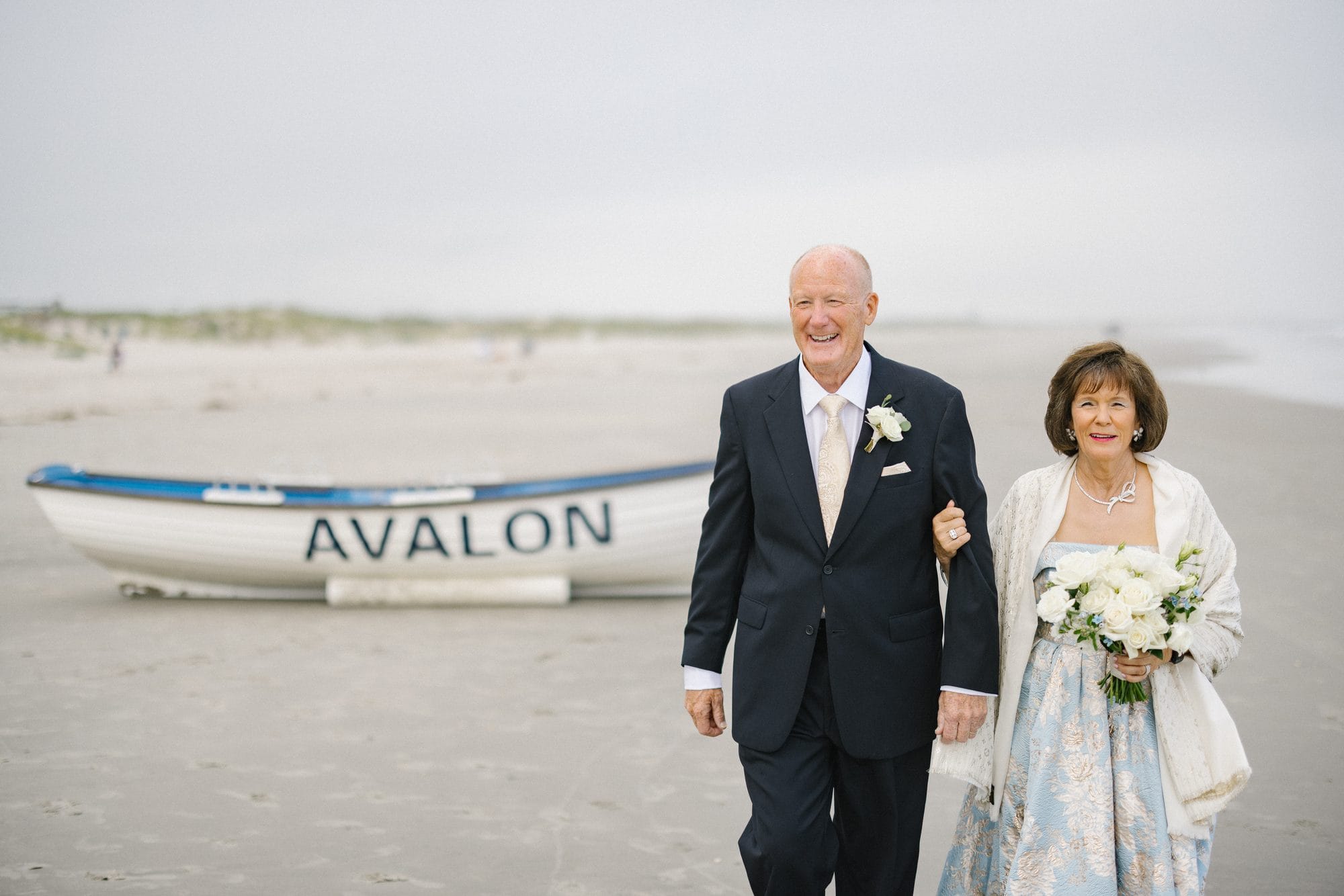 A couple walking arm in arm past the Avalon lifeguard boat during their 50th anniversary vow renewal on the beach