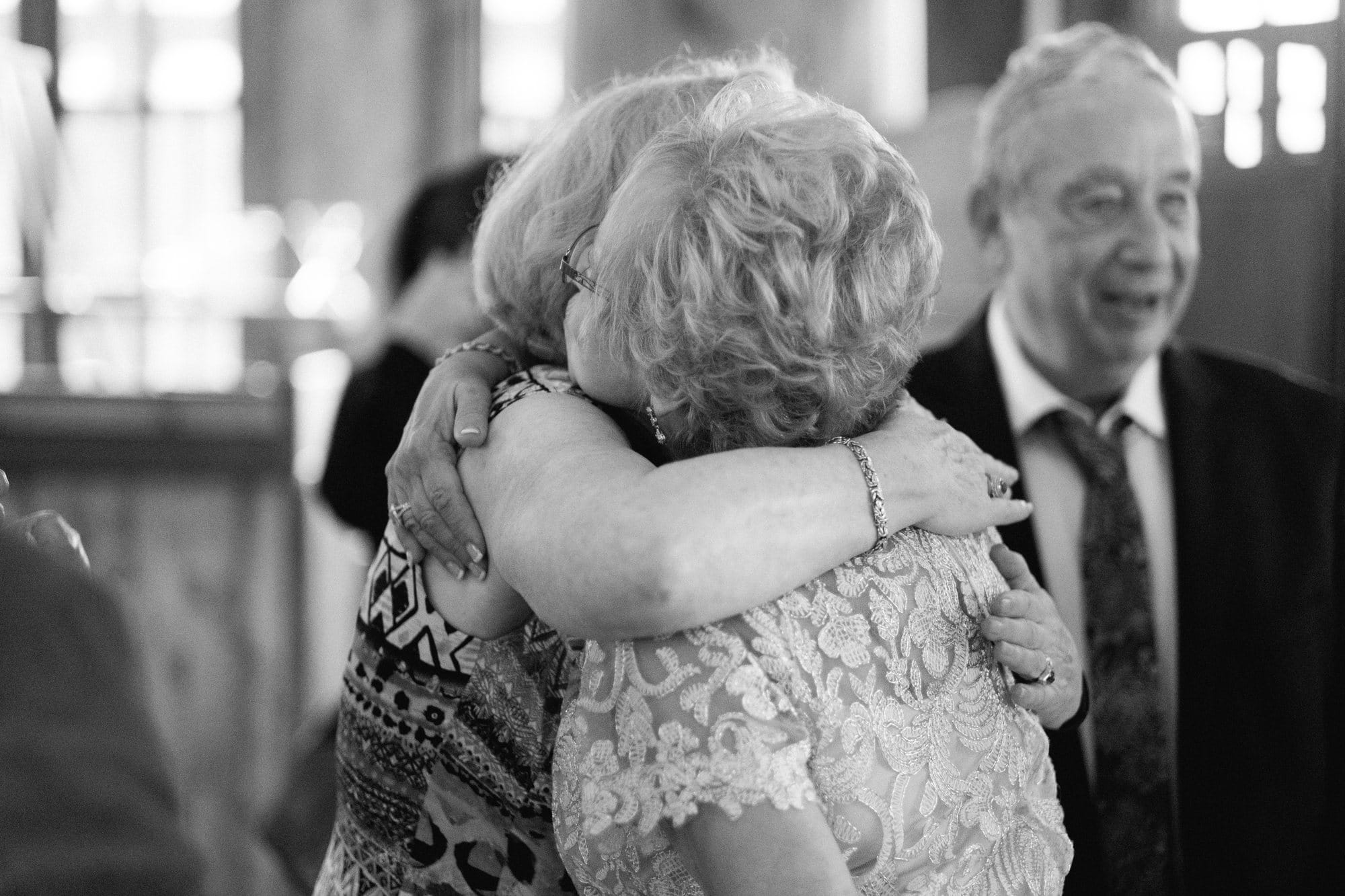 A black and white candid of an emotional embrace at a 50th wedding anniversary vow renewal
